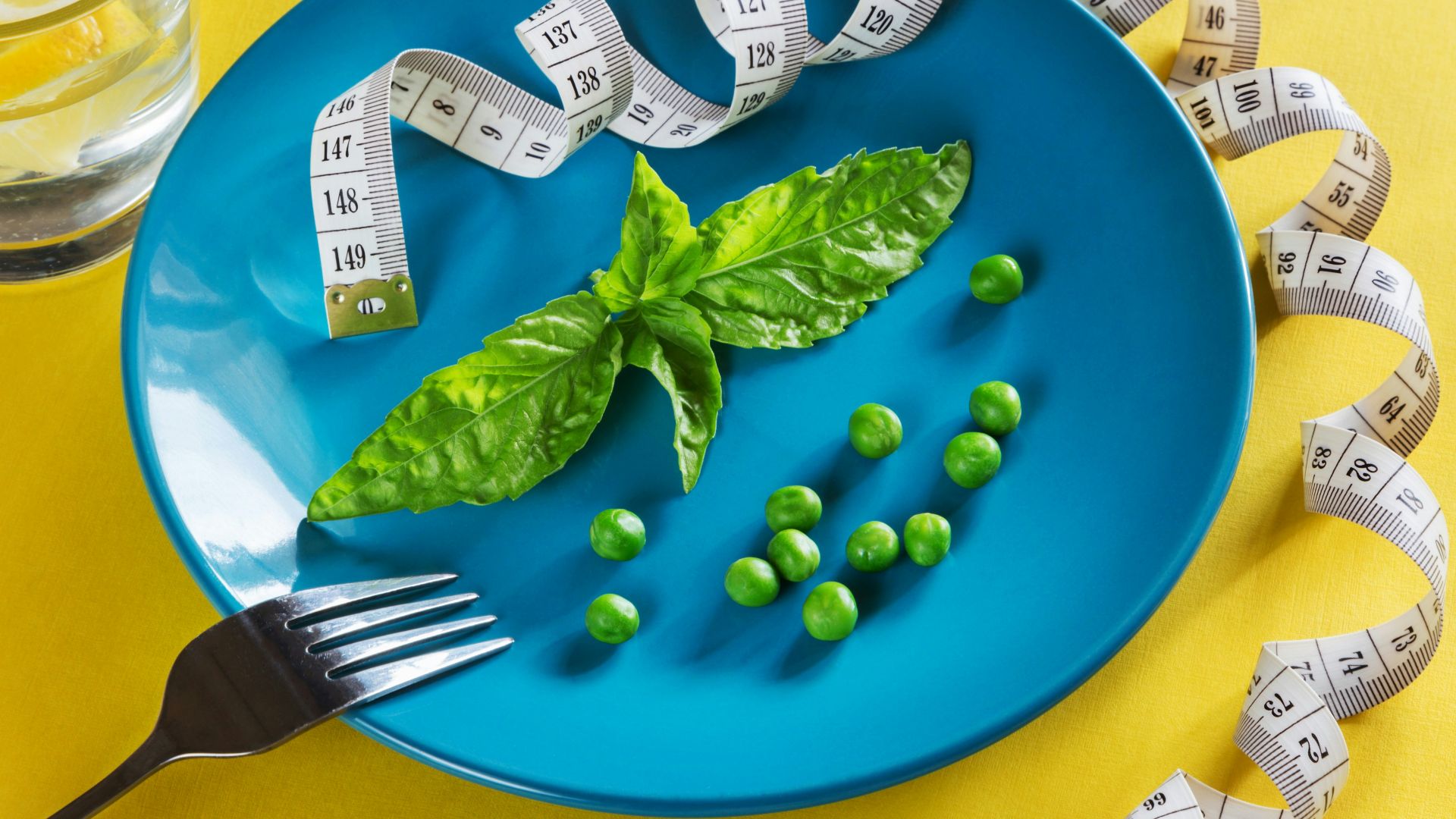 a blue plate topped with green vegetables and measuring tape