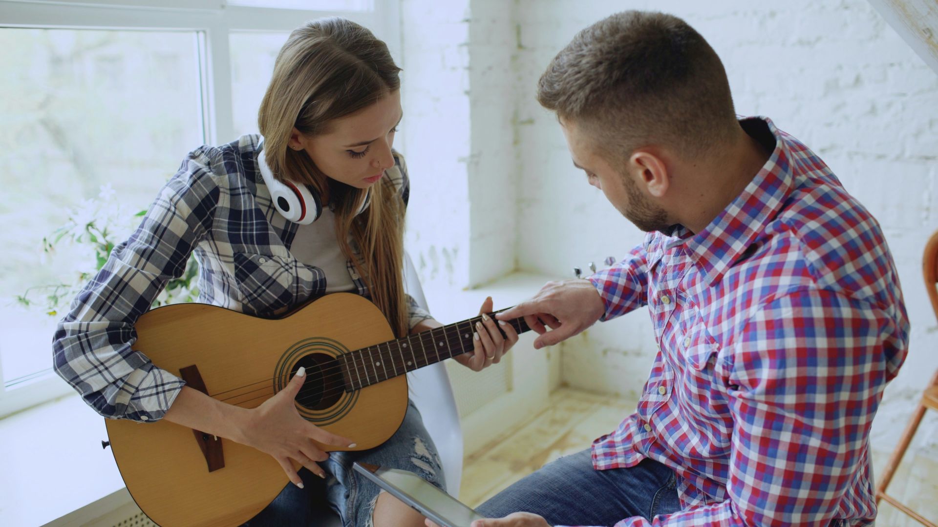 Man teaching woman to play guitar indoors