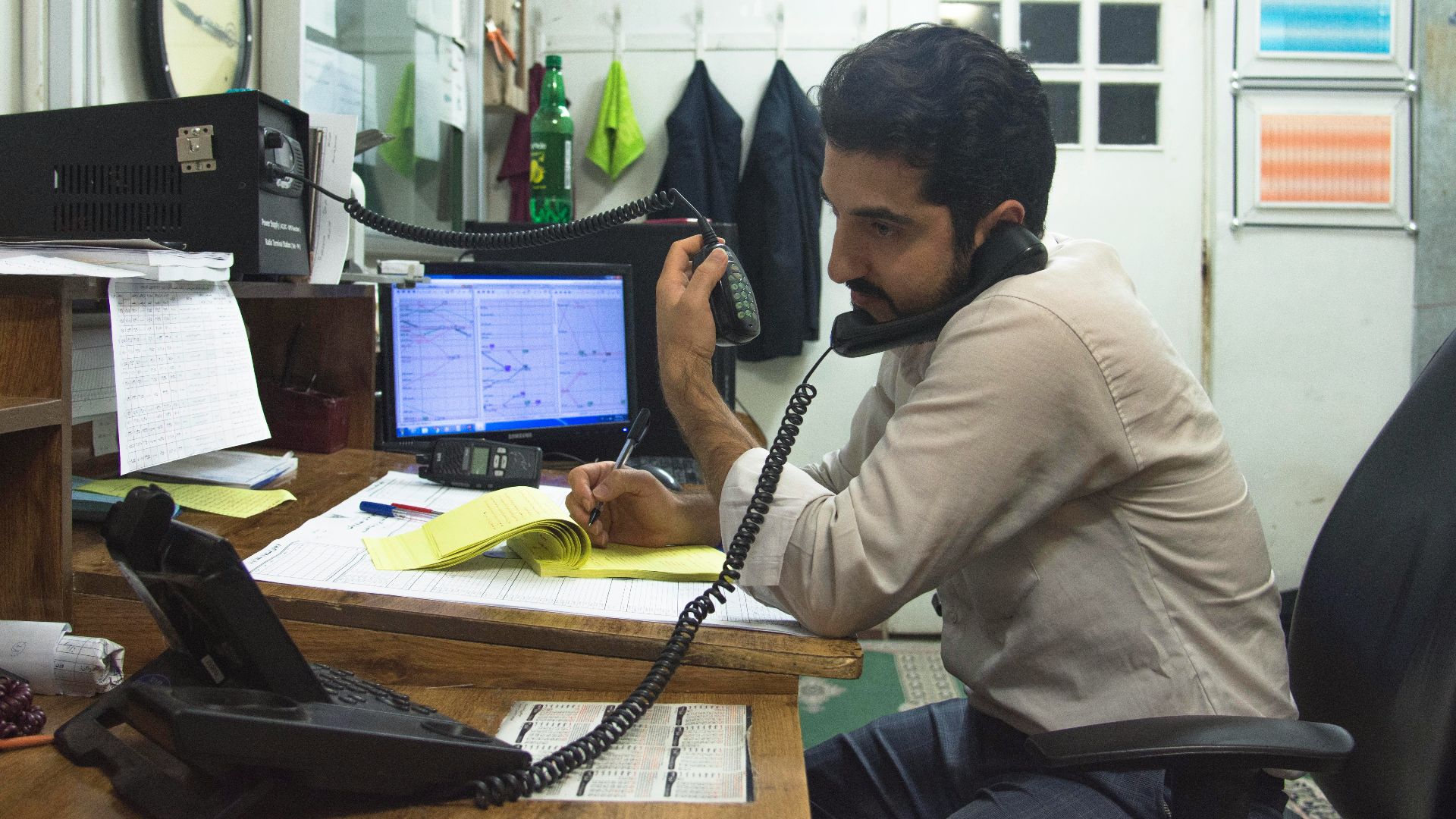 a man sitting at a desk talking on a phone
