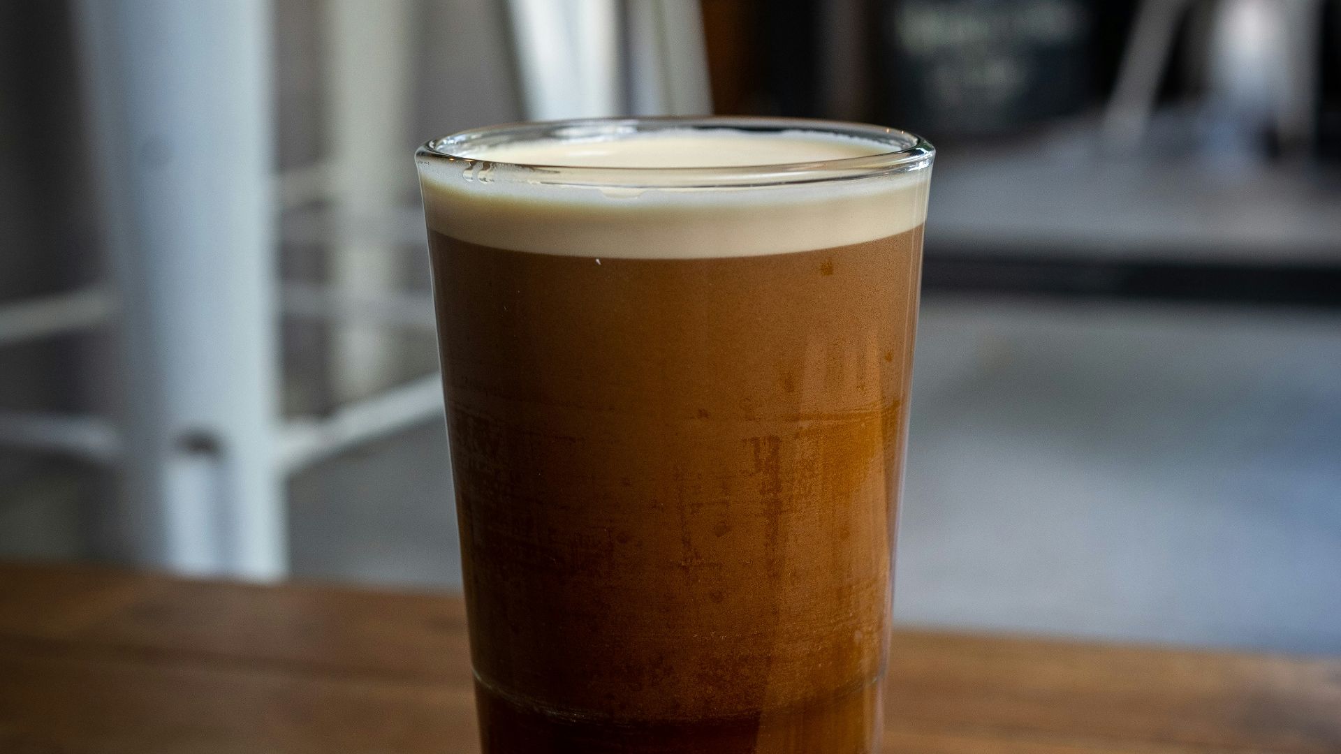 a glass filled with liquid sitting on top of a wooden table