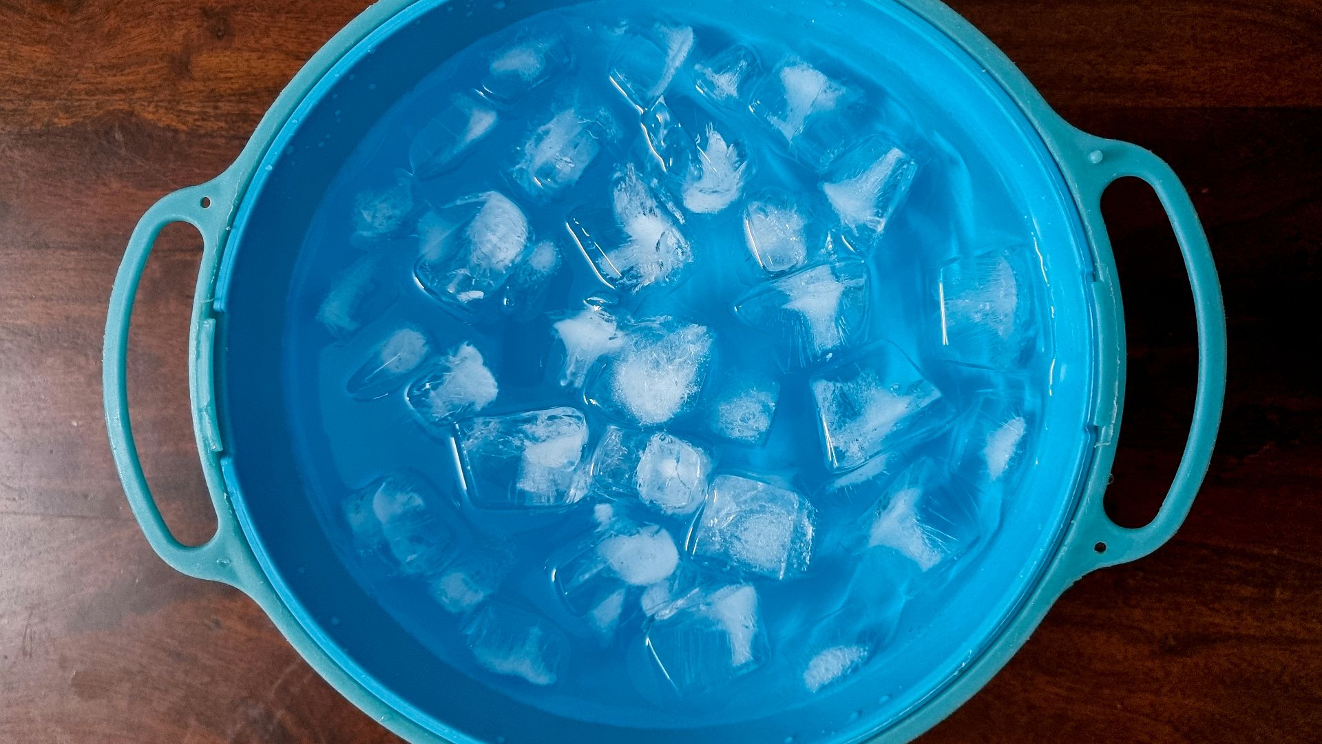 an ice bucket filled with ice cubes on top of a wooden table