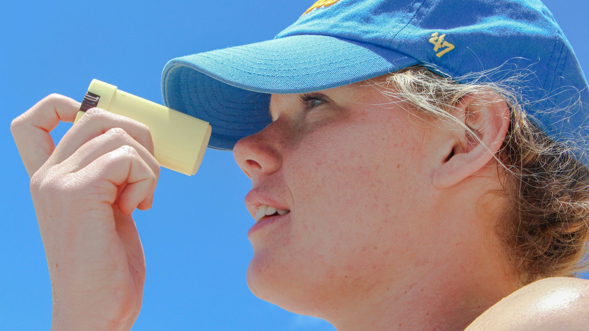 a woman wearing a blue hat looking through a magnifying glass
