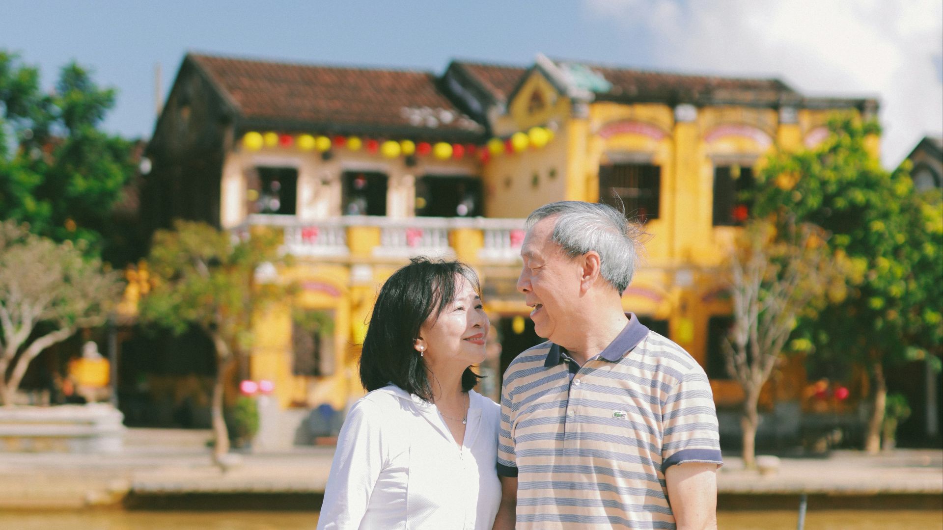 Couple holding hands by a river with buildings