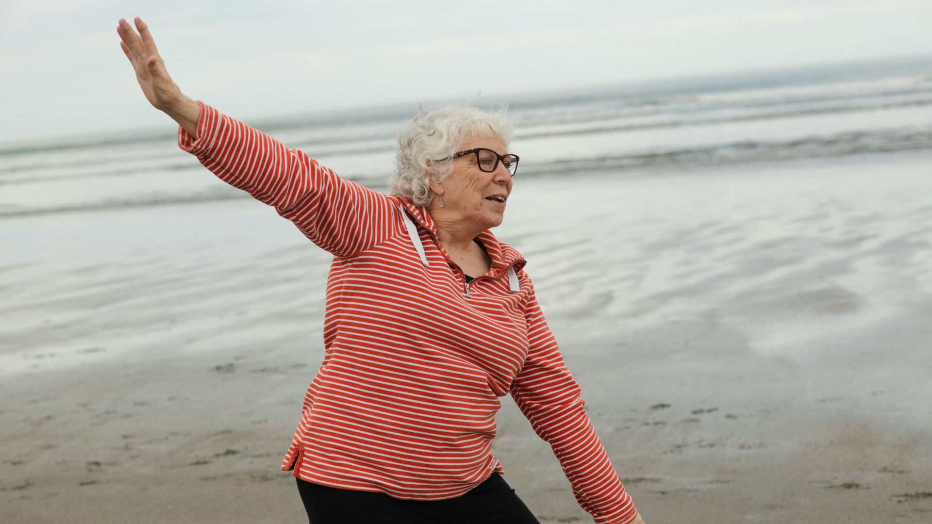Woman practices tai chi on the beach.