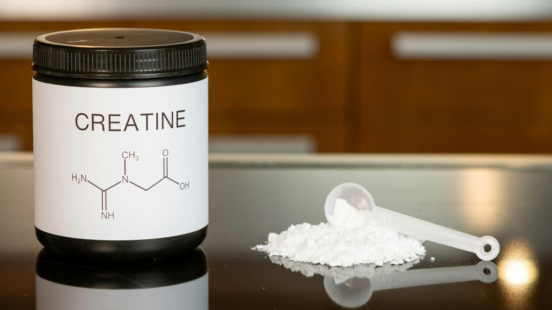 a bottle of creatine next to a spoon on a table