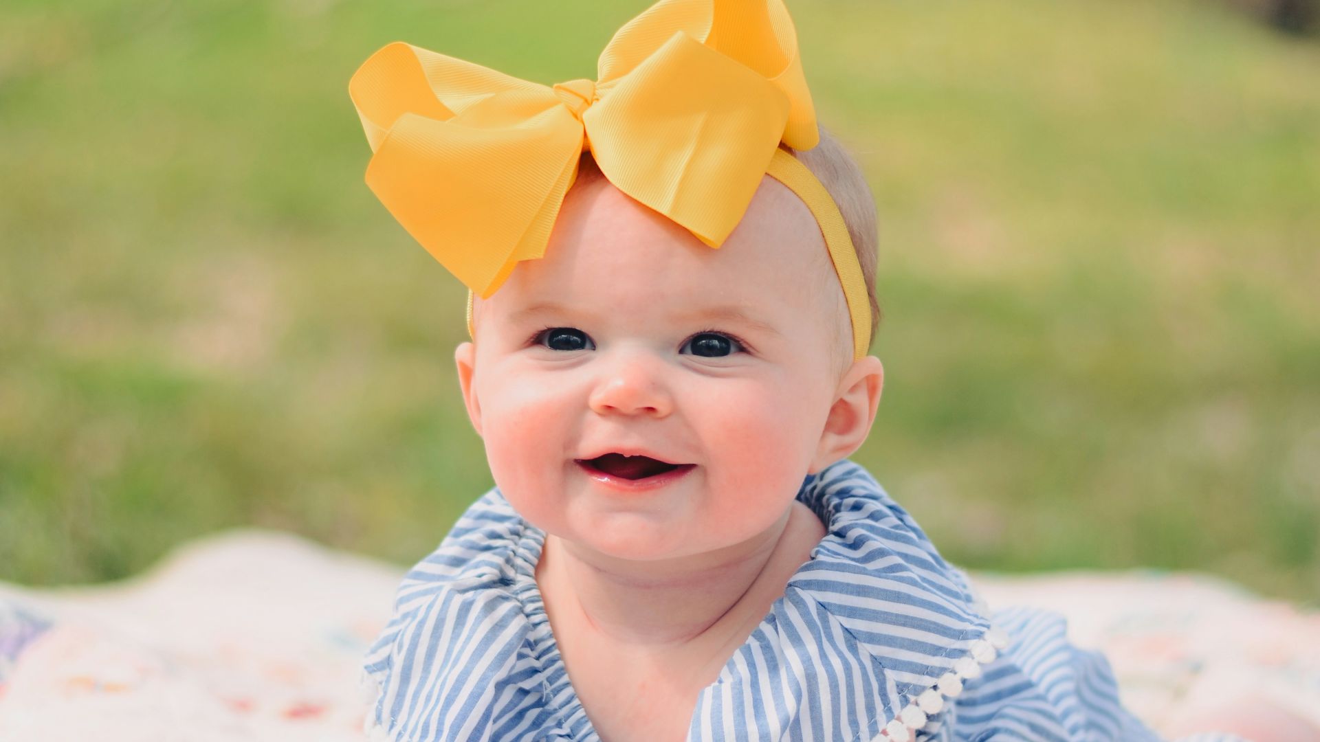 smiling baby lying forward on pink textile