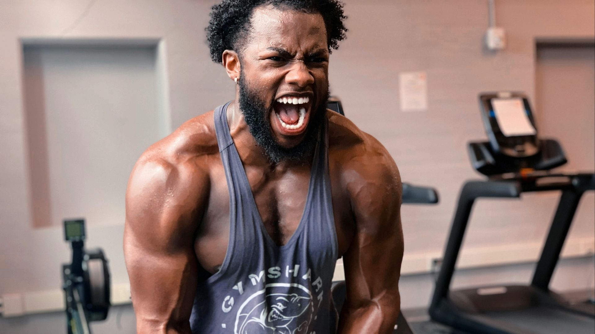 a man with a beard and no shirt on in a gym