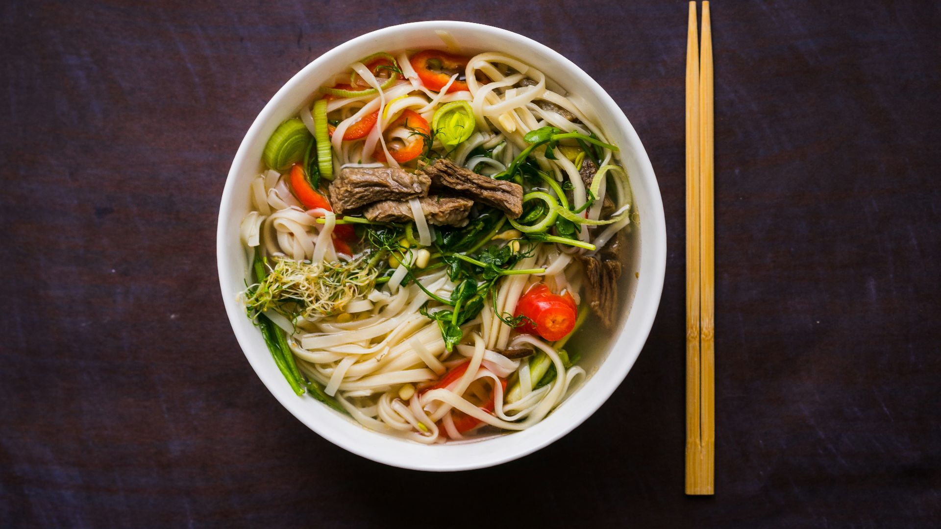 a bowl of noodle soup with chopsticks on the side