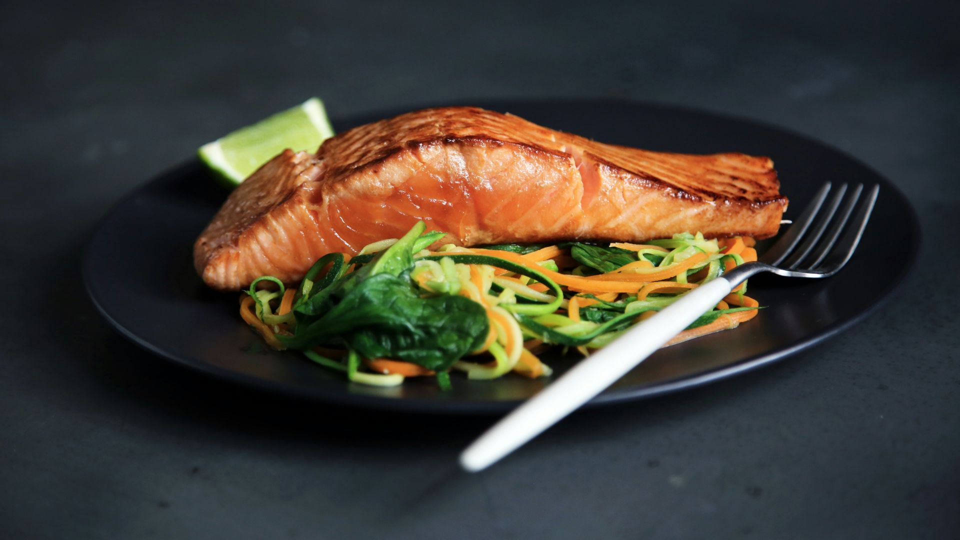 grilled fish, cooked vegetables, and fork on plate