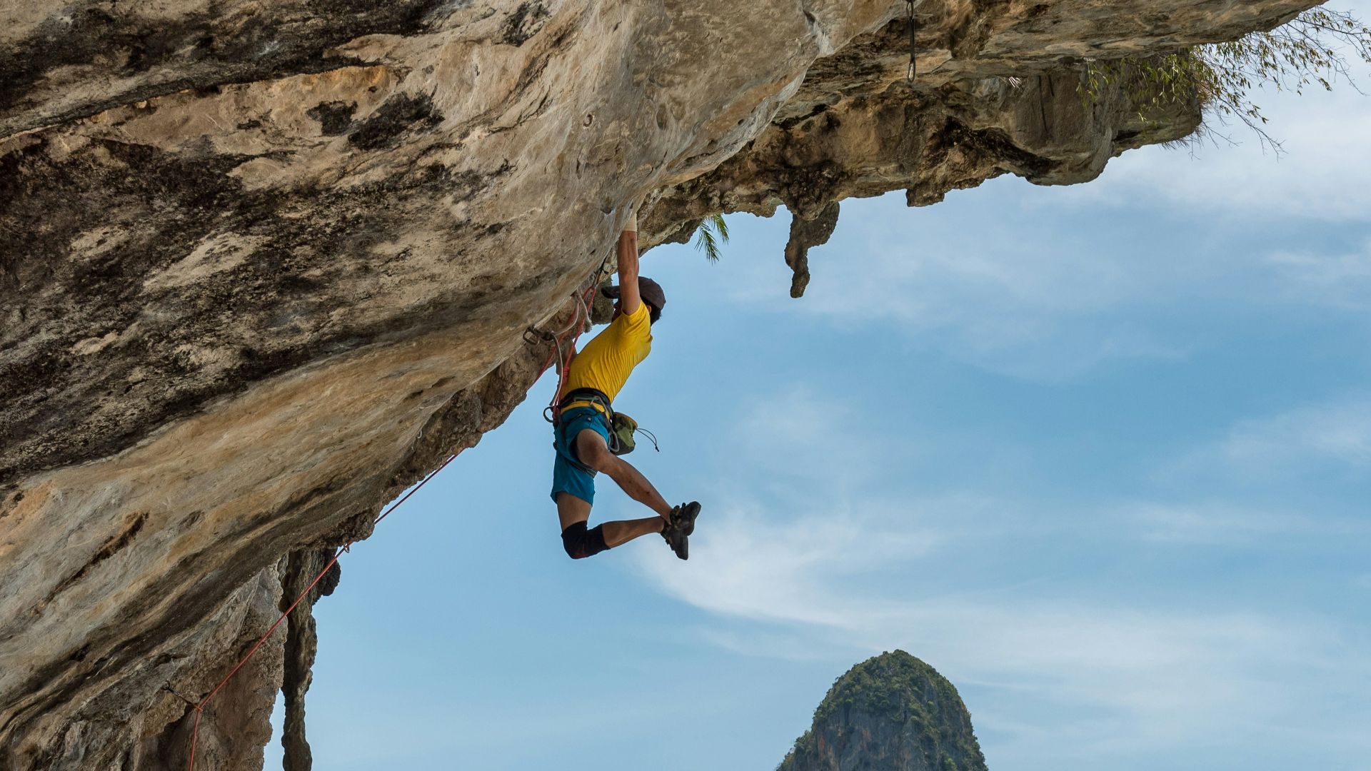 man climbing cliff beside beach