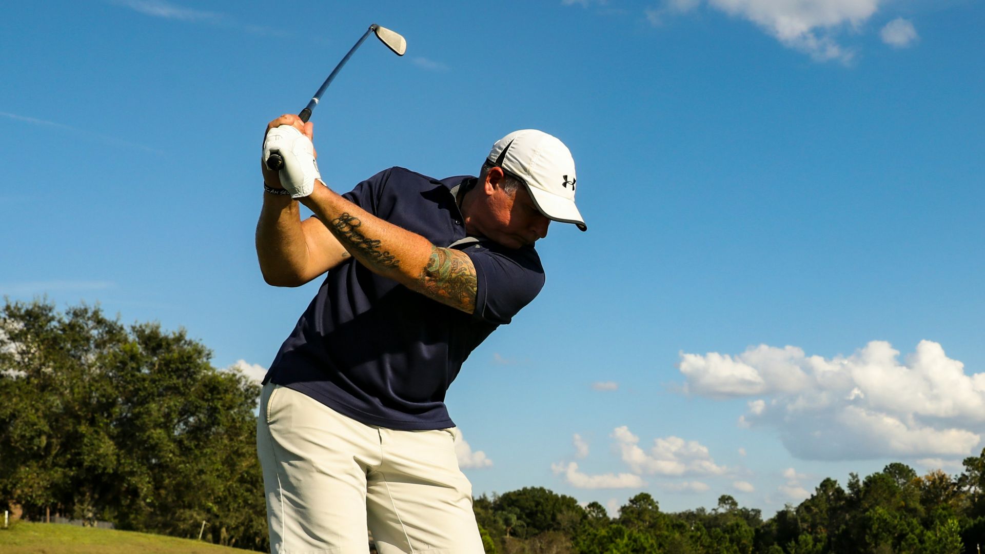 man in black shirt and white shorts playing golf during daytime