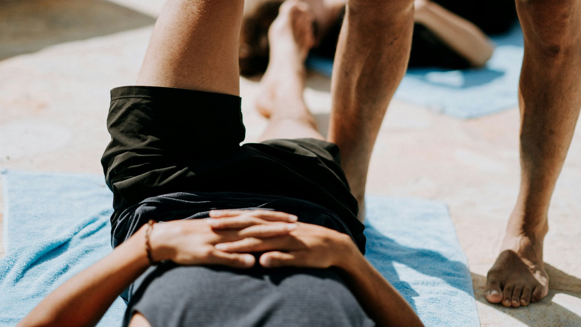man lying on floor near man standing holding his leg