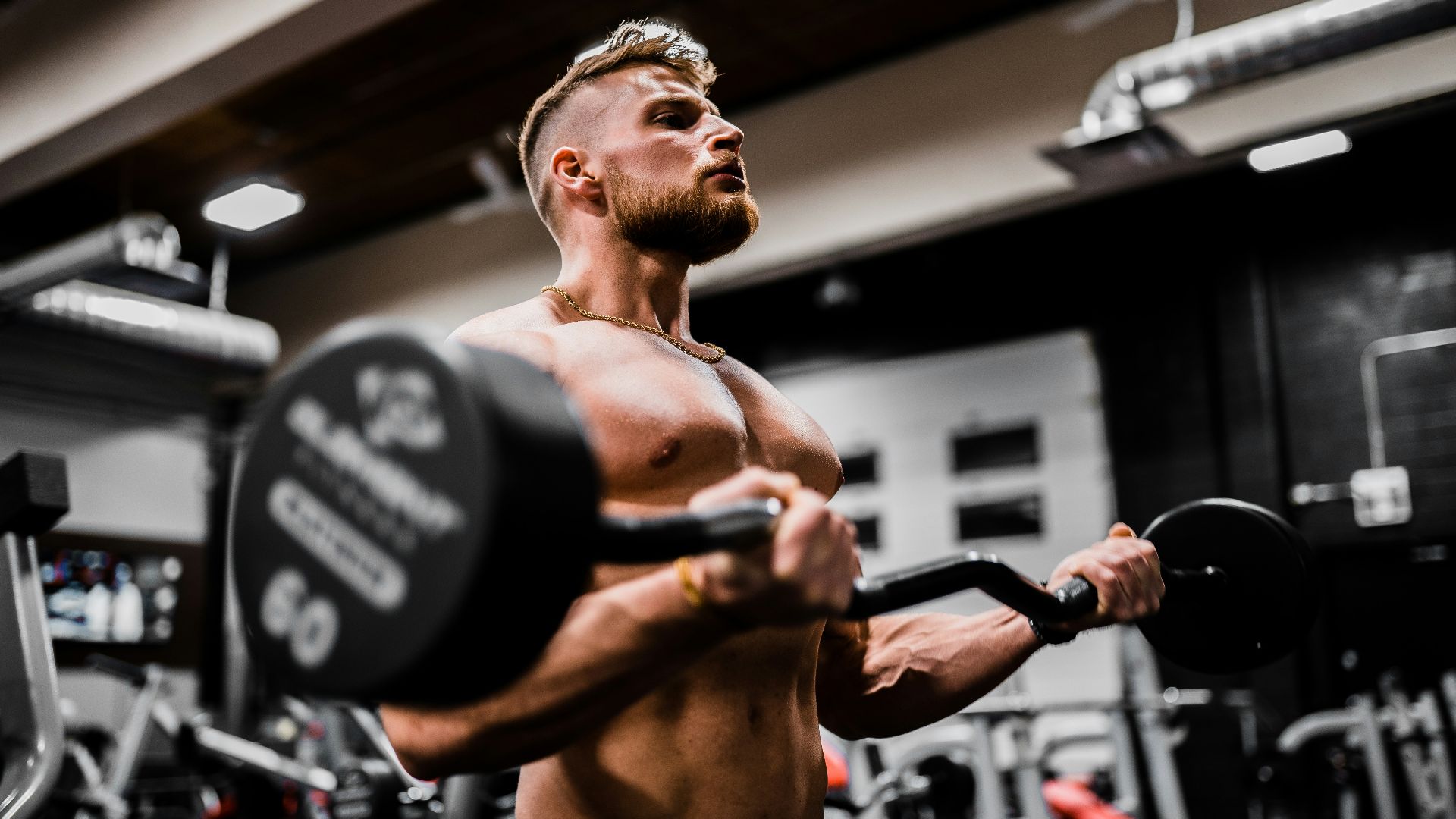 topless man in black shorts carrying black dumbbell