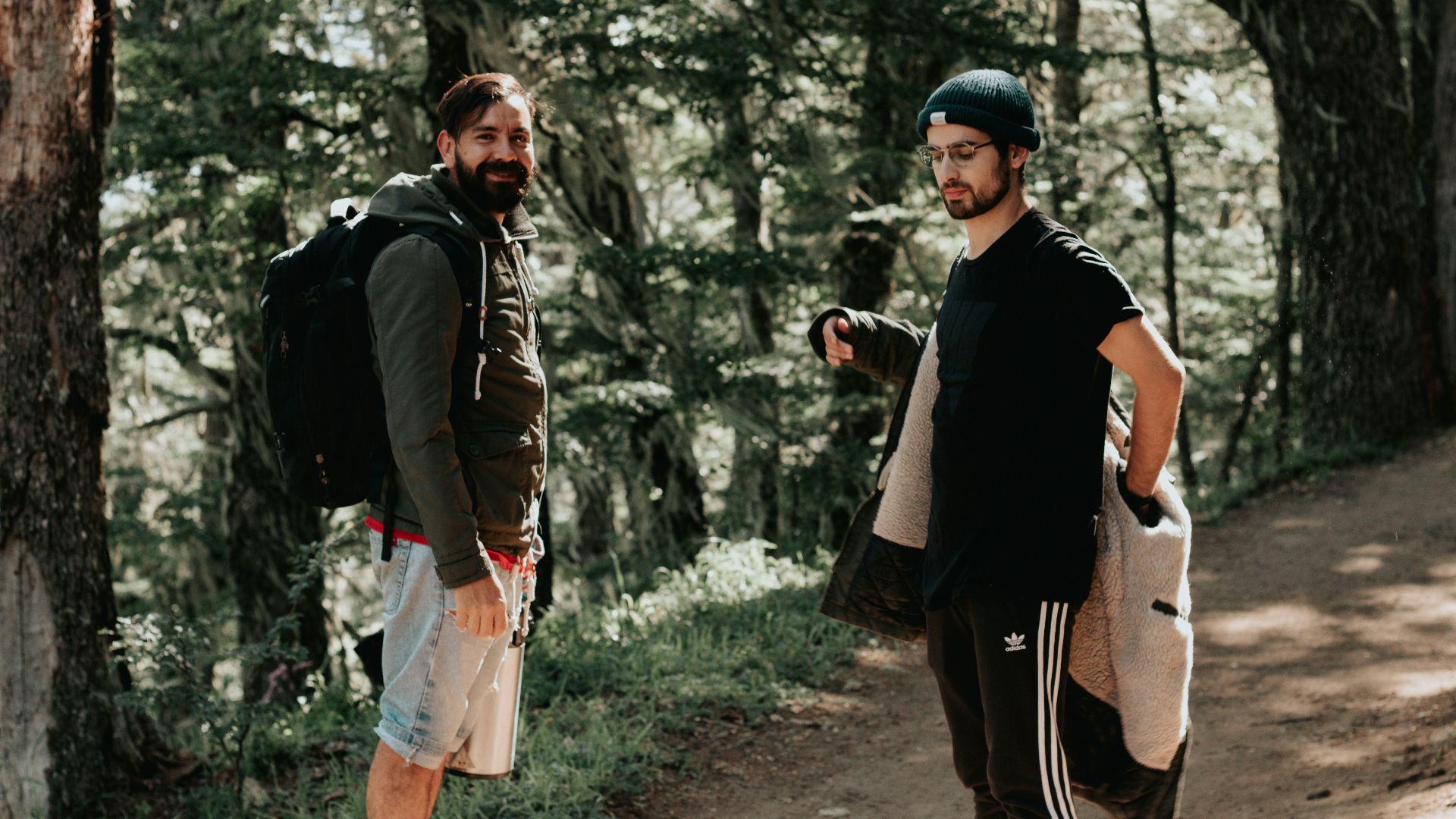 man in black jacket and white shorts standing beside woman in black jacket