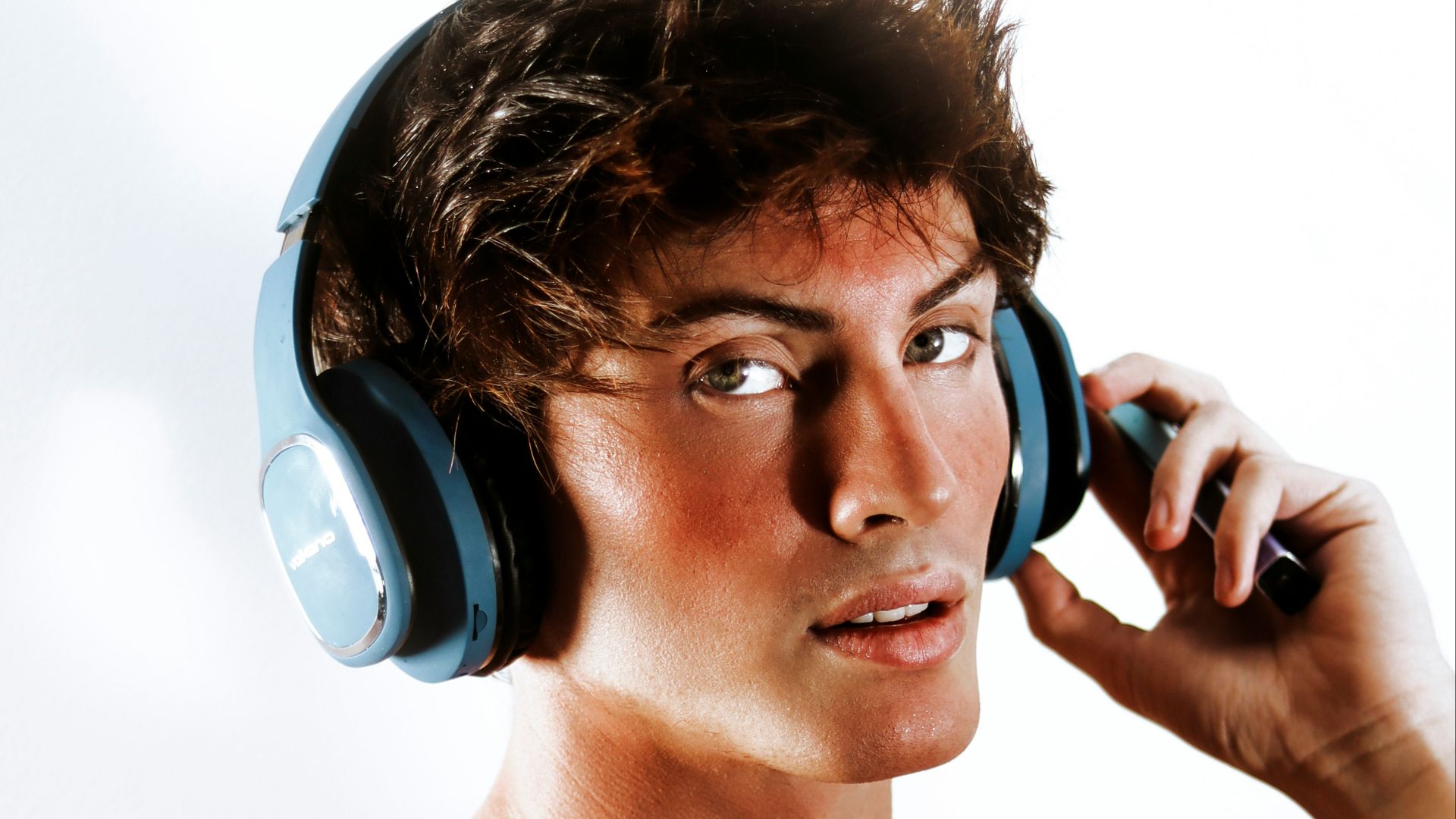 A shirtless man with headphones on talking on a cell phone