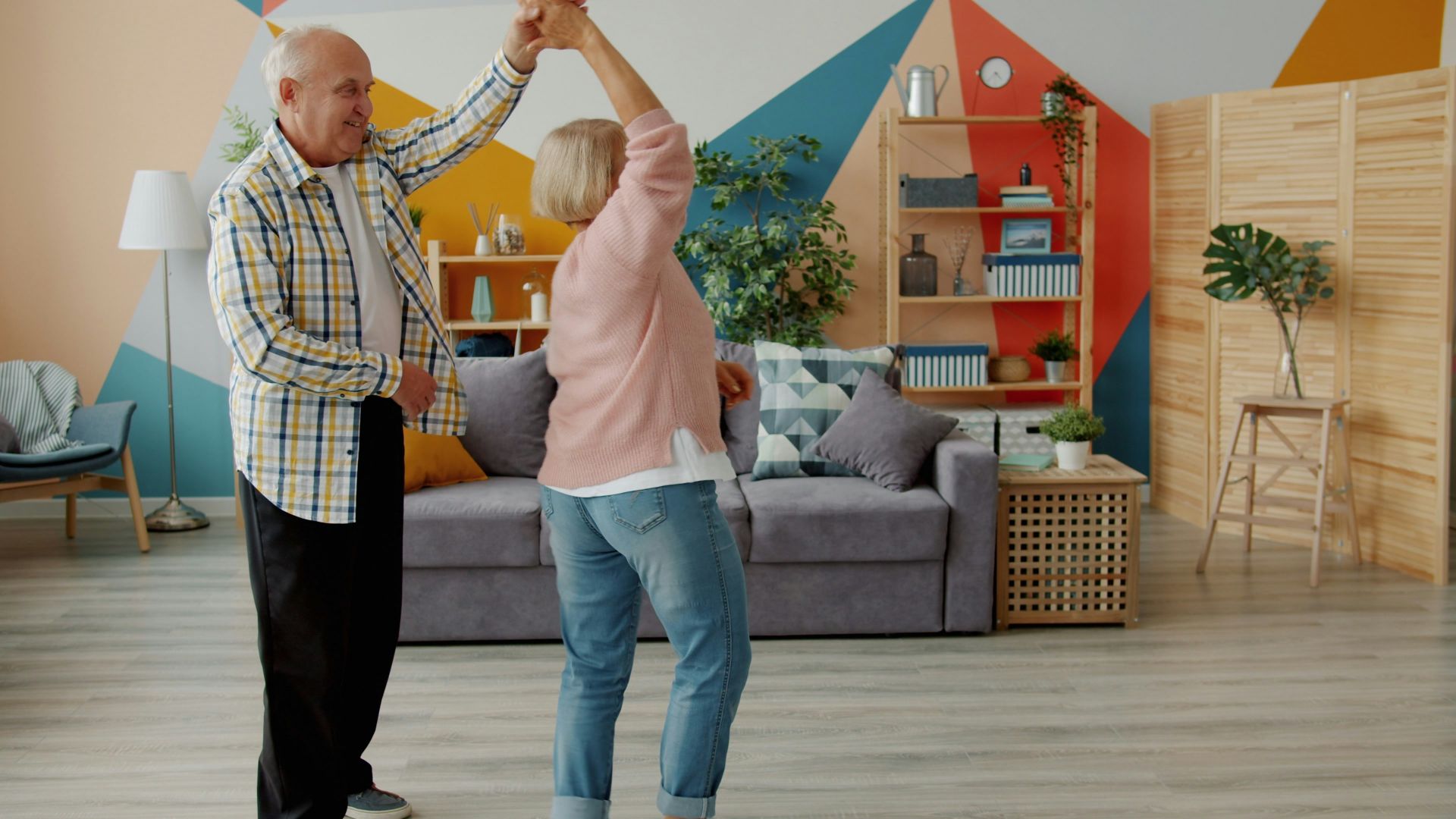 Elderly couple dancing joyfully in a living room.