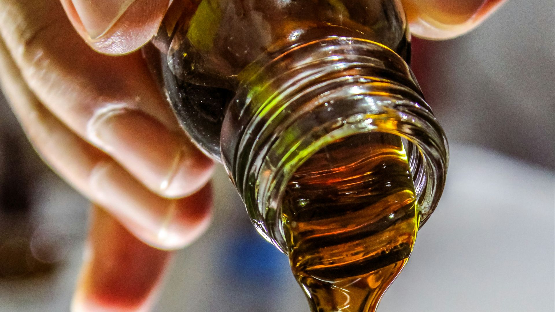 person holding clear drinking glass with brown liquid