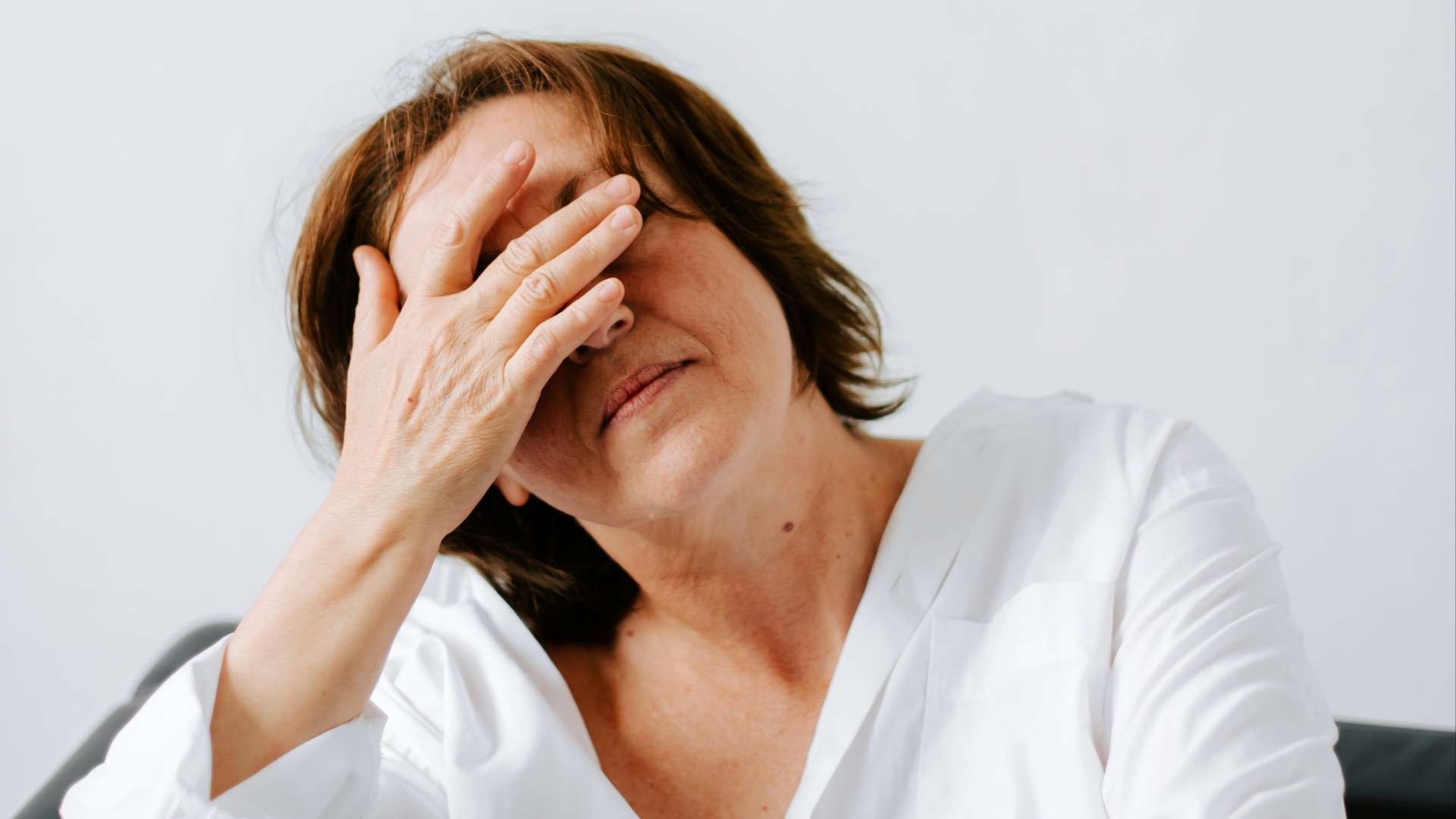 a woman sitting on a couch holding her hands to her face