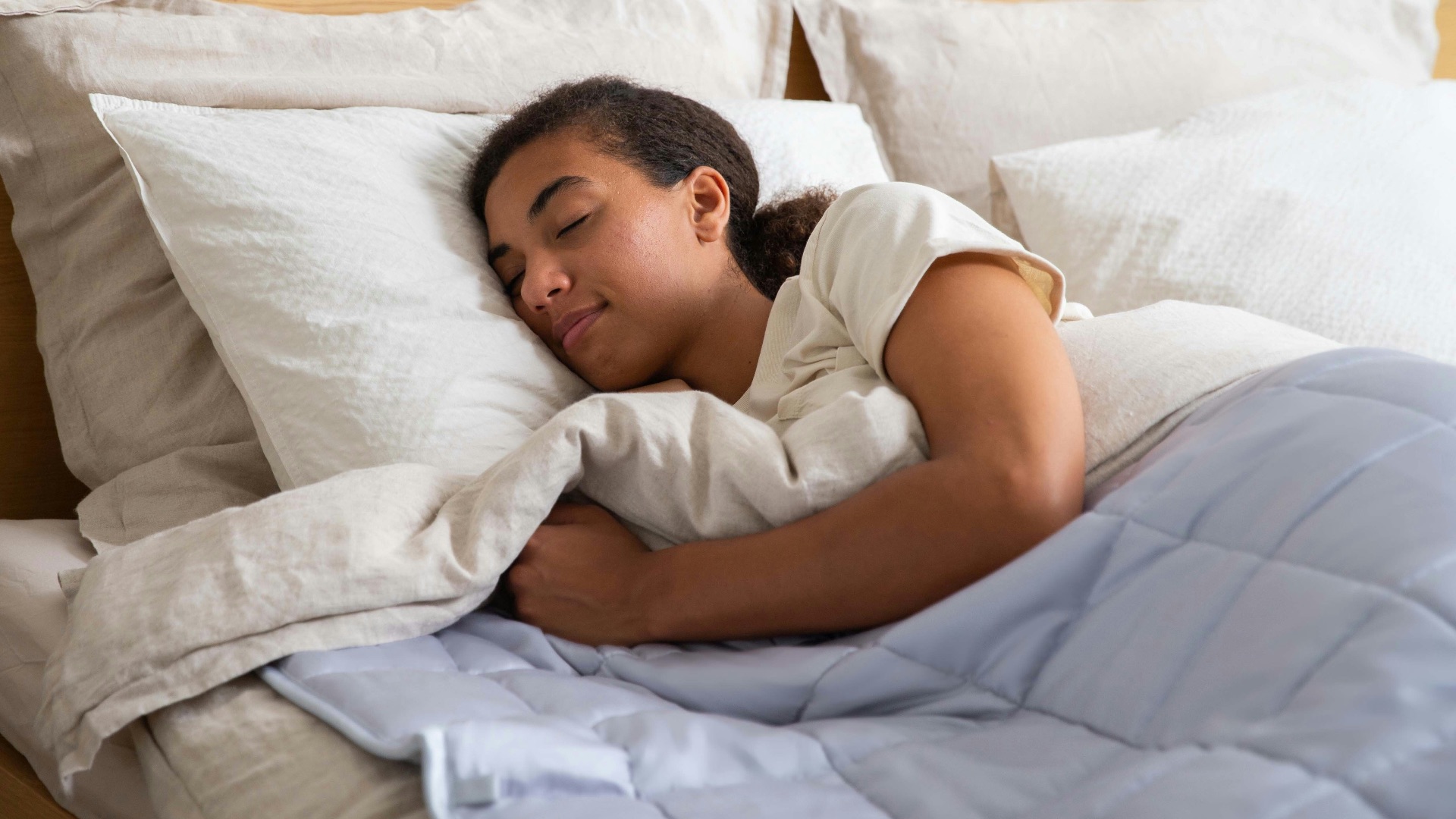 a young girl sleeping in a bed with white sheets