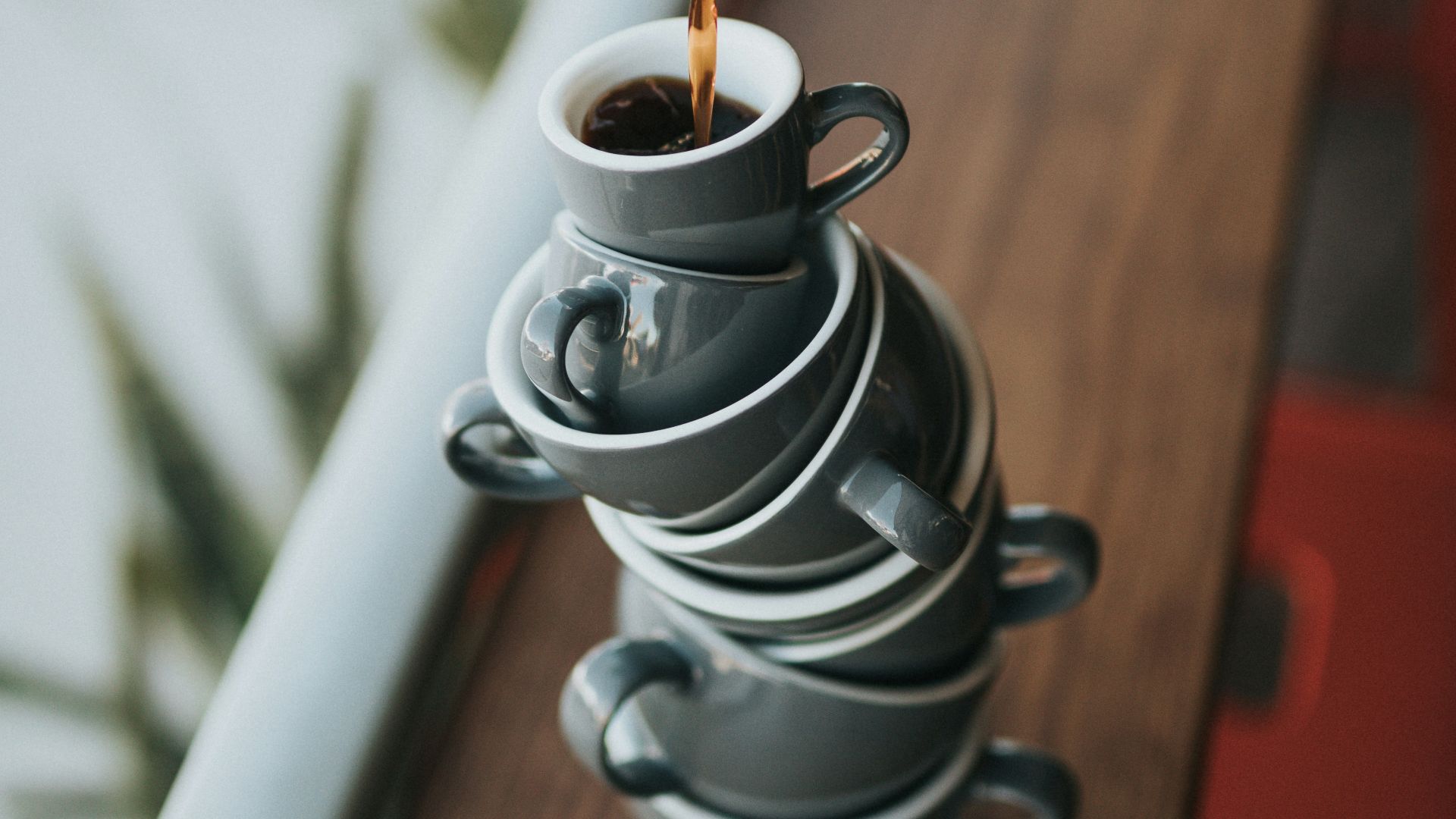 person holding gray stainless steel pitcher bside window