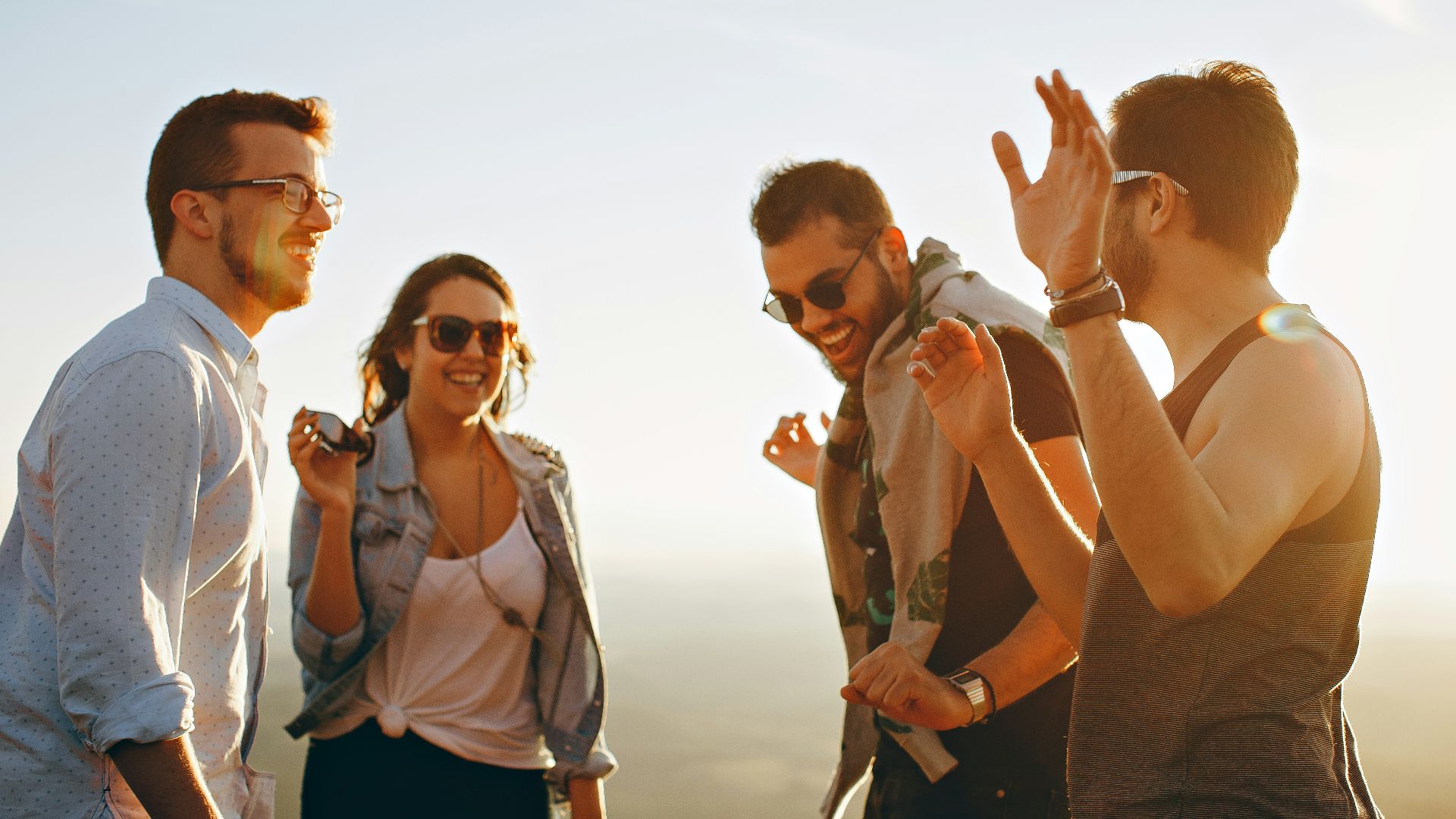 three men and one woman laughing during daytime