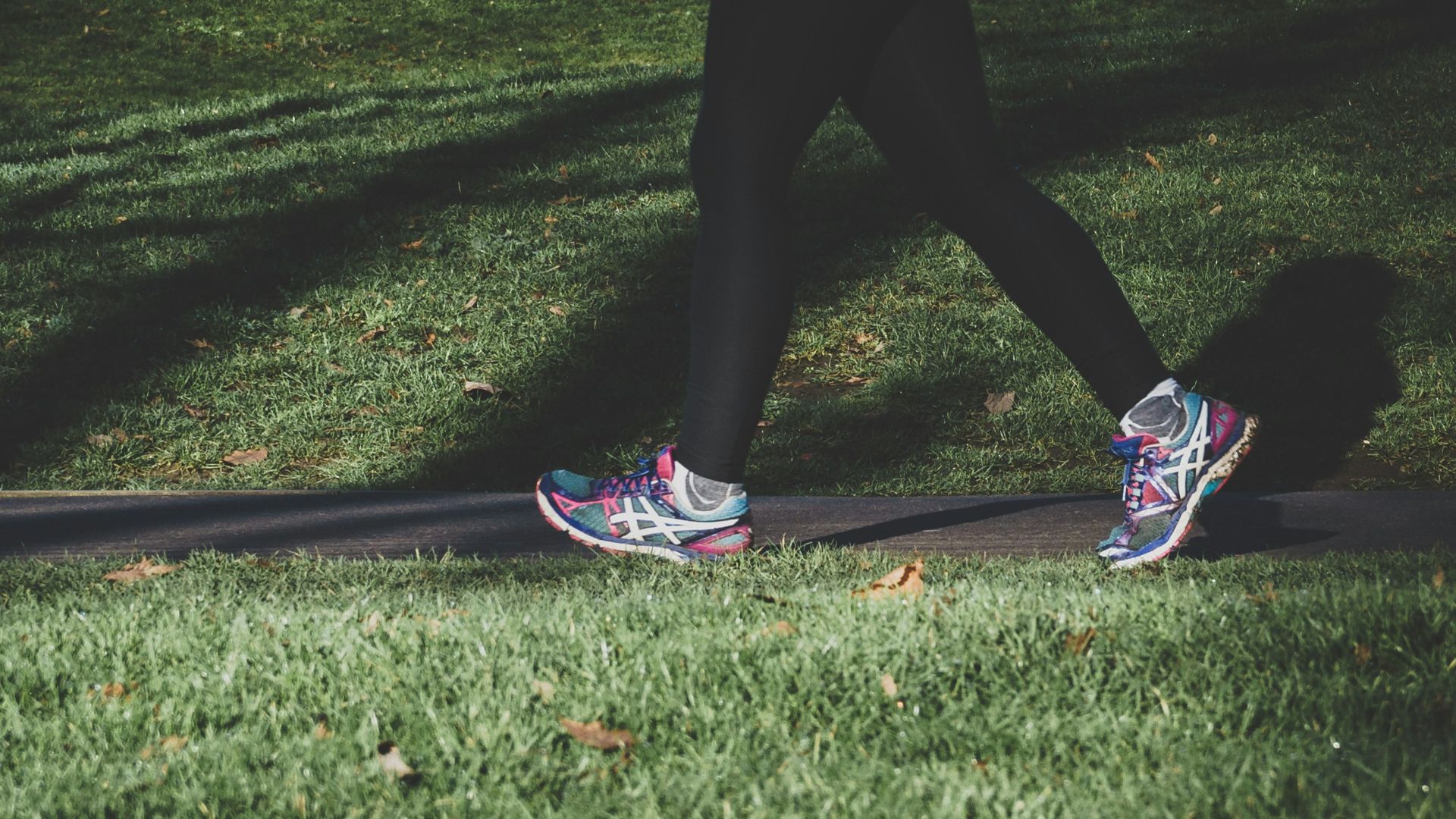 shallow focus photography of person walking on road between grass