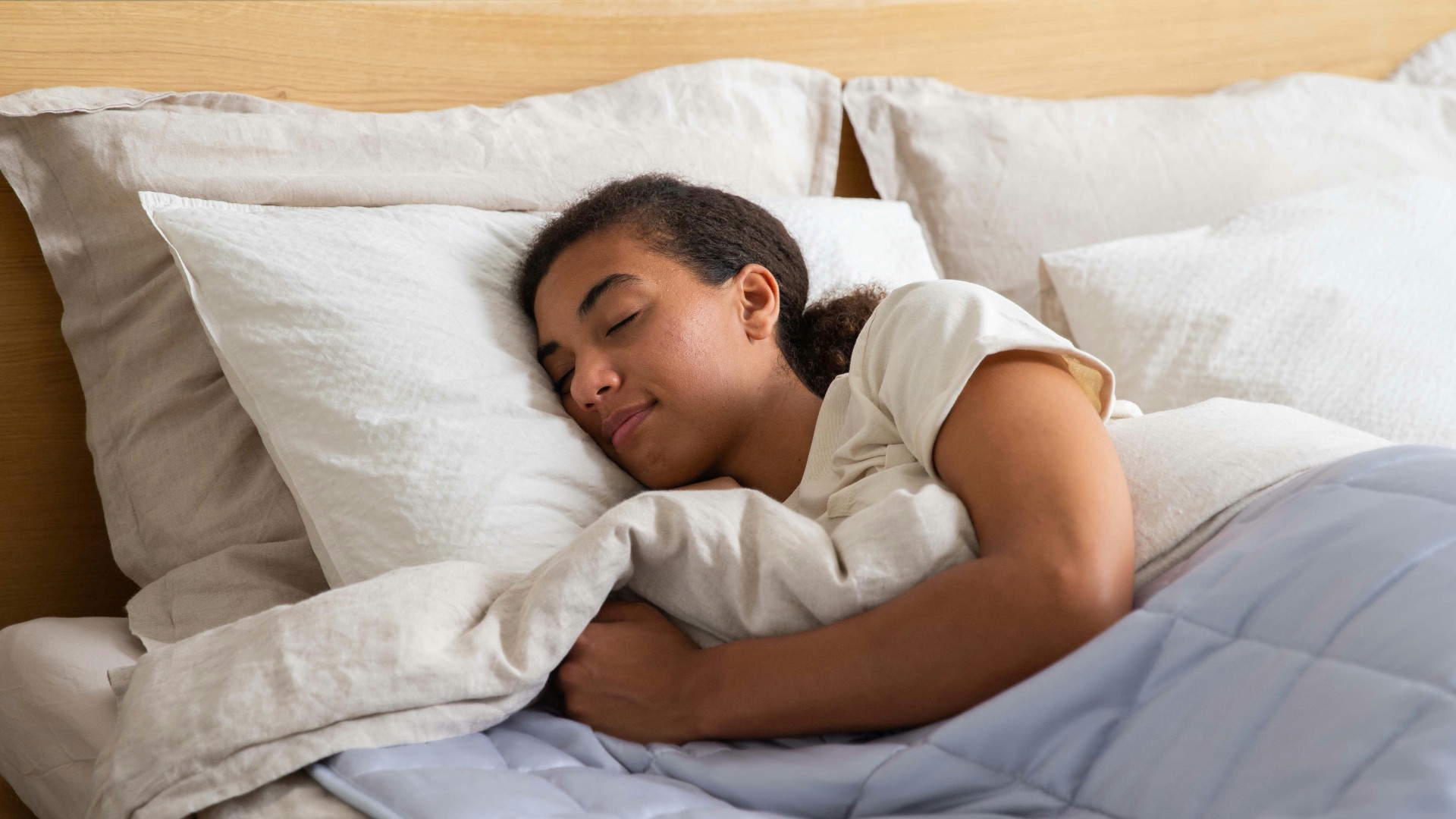 a young girl sleeping in a bed with white sheets