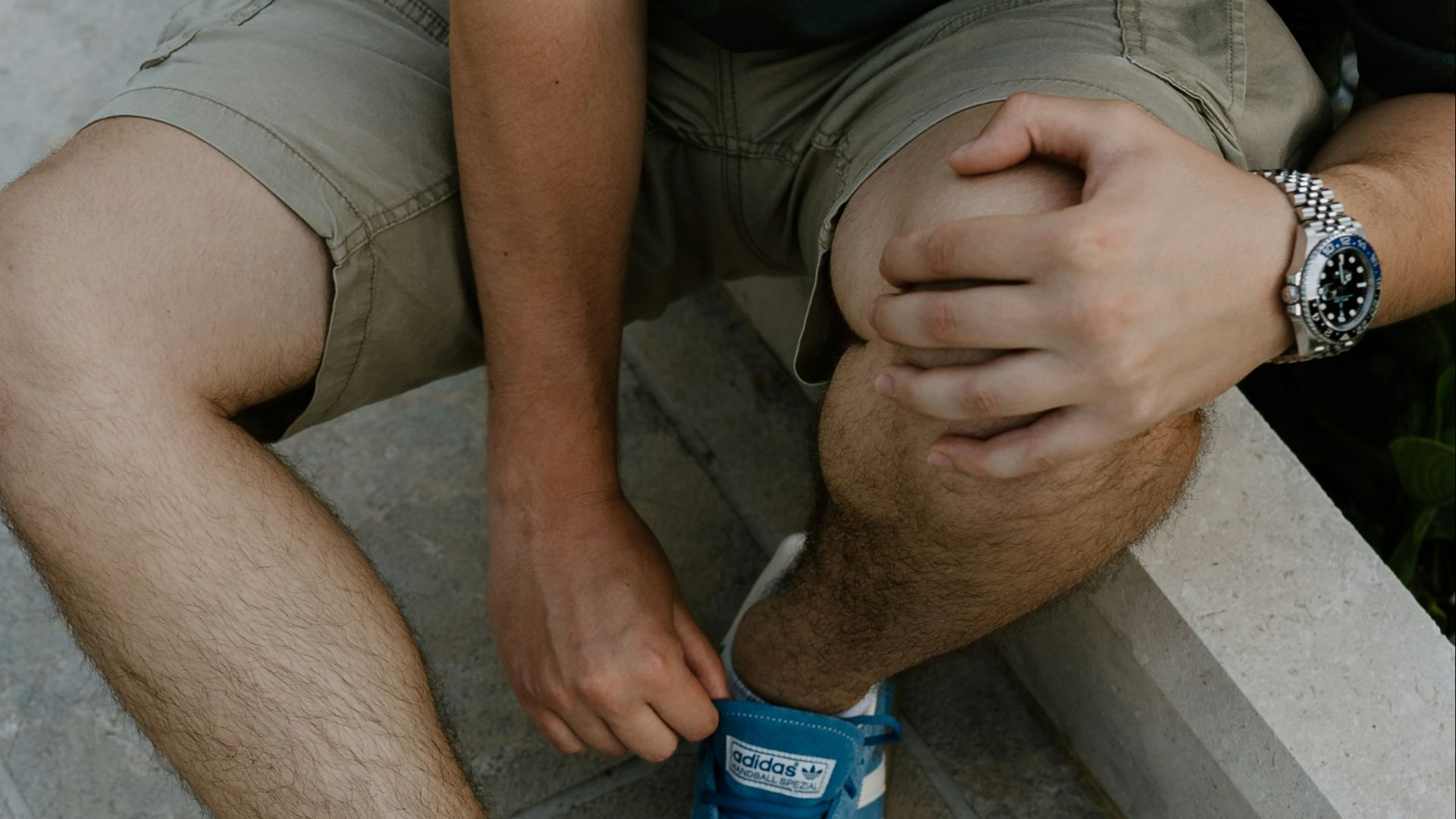 A man sitting on a ledge tying his shoes