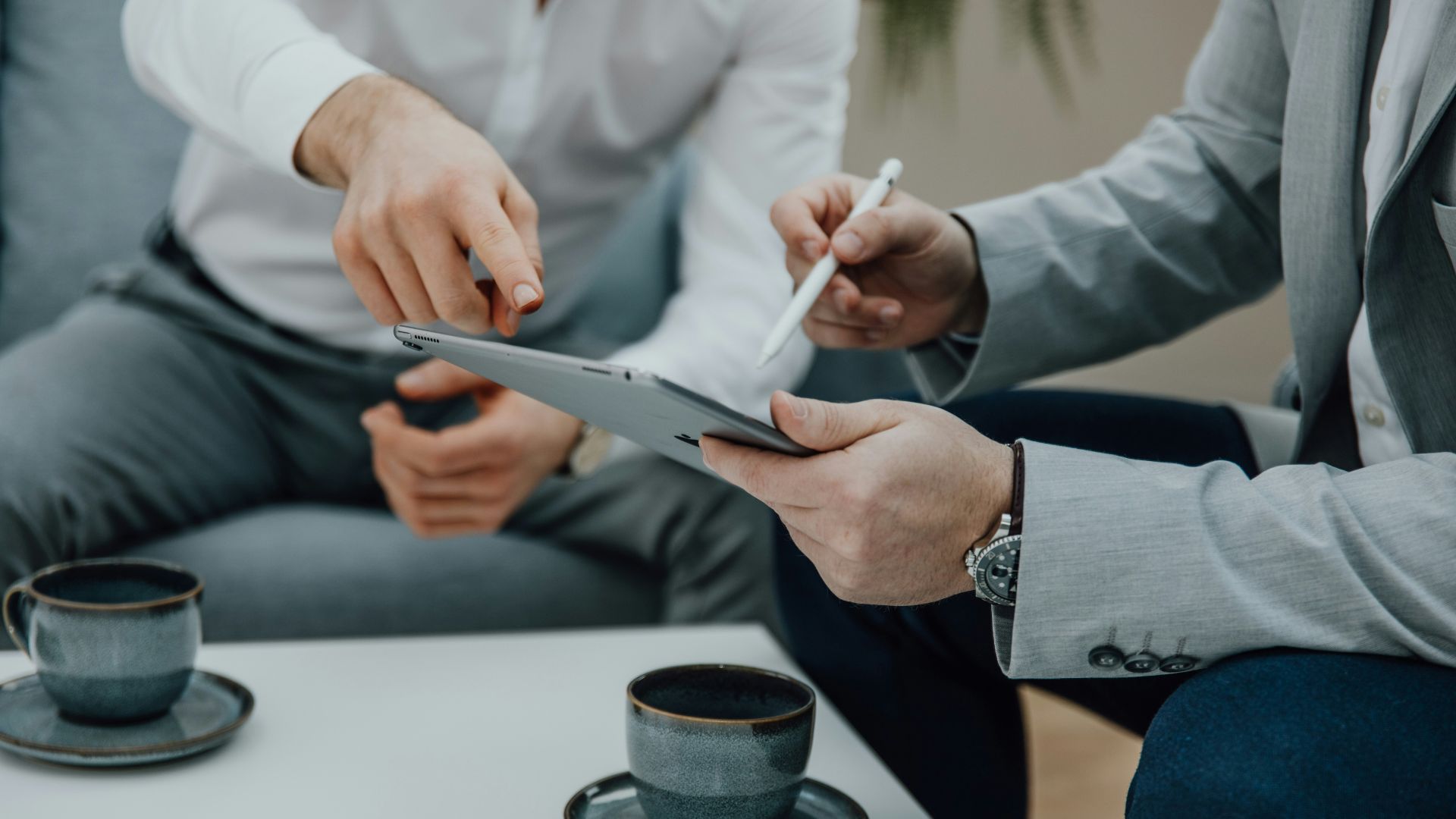 two people sitting at a table with a tablet