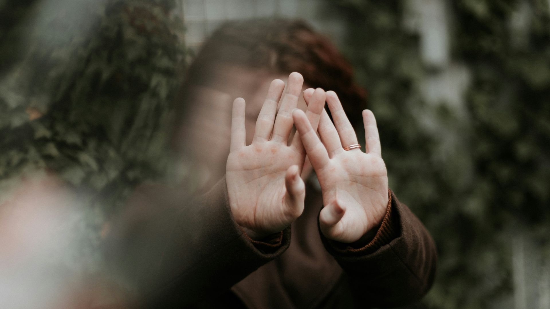 person in brown long sleeve shirt covering face with hand