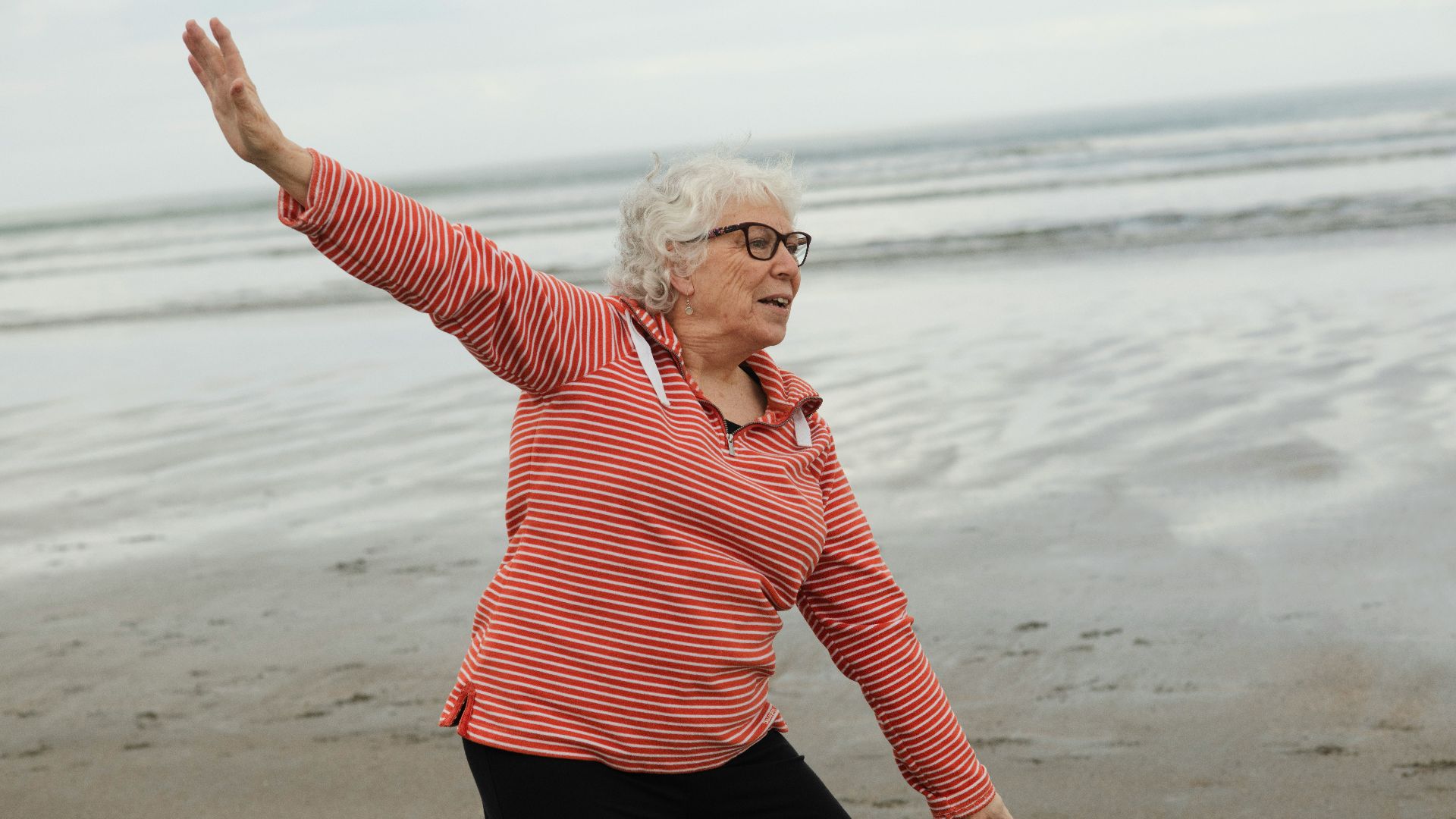 Woman practices tai chi on the beach.
