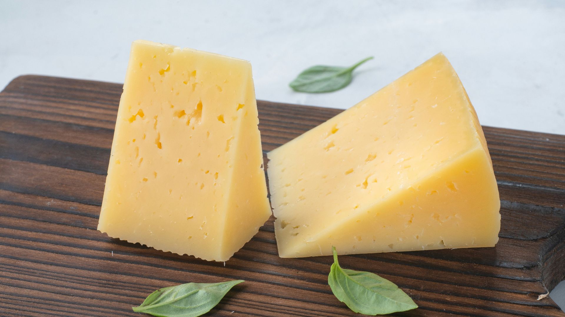 a couple of pieces of cheese sitting on top of a wooden cutting board