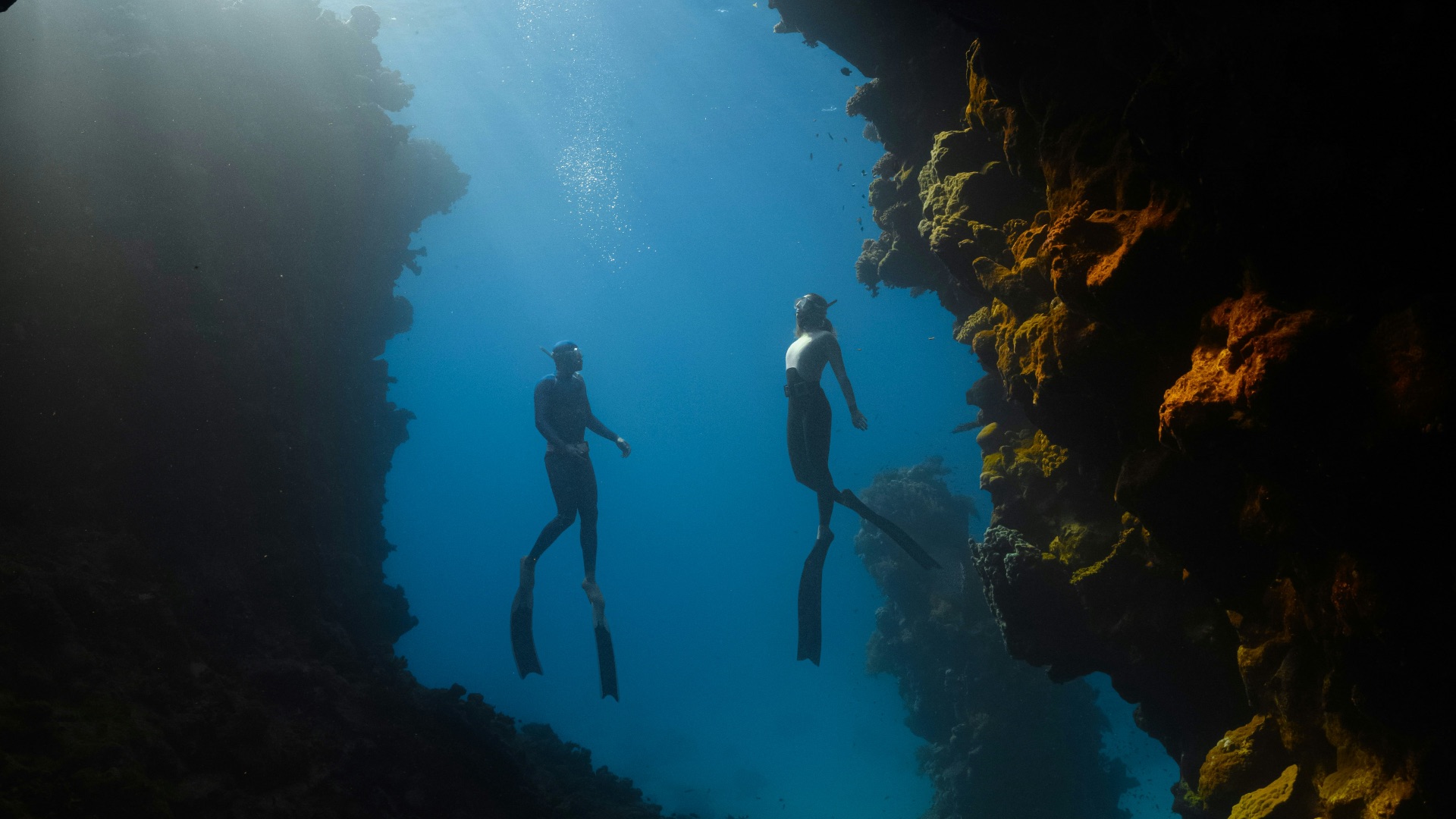 a couple of people are swimming in a cave