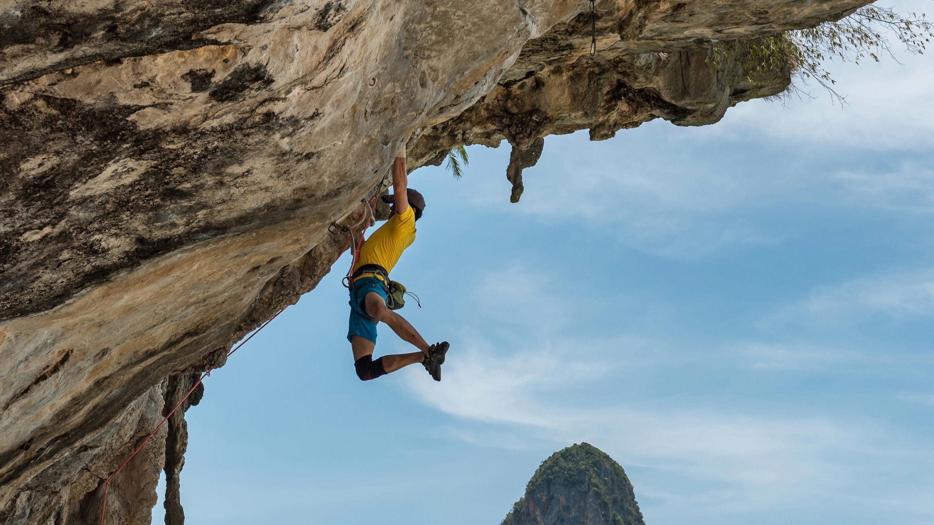 man climbing cliff beside beach