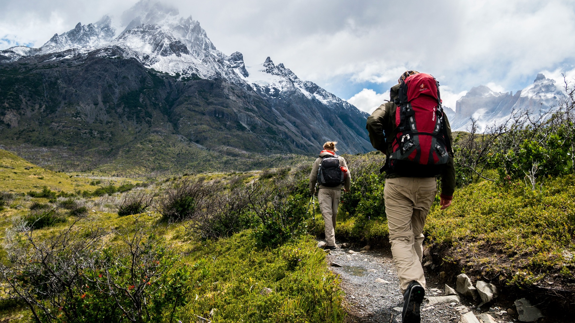 two person walking towards mountain covered with snow