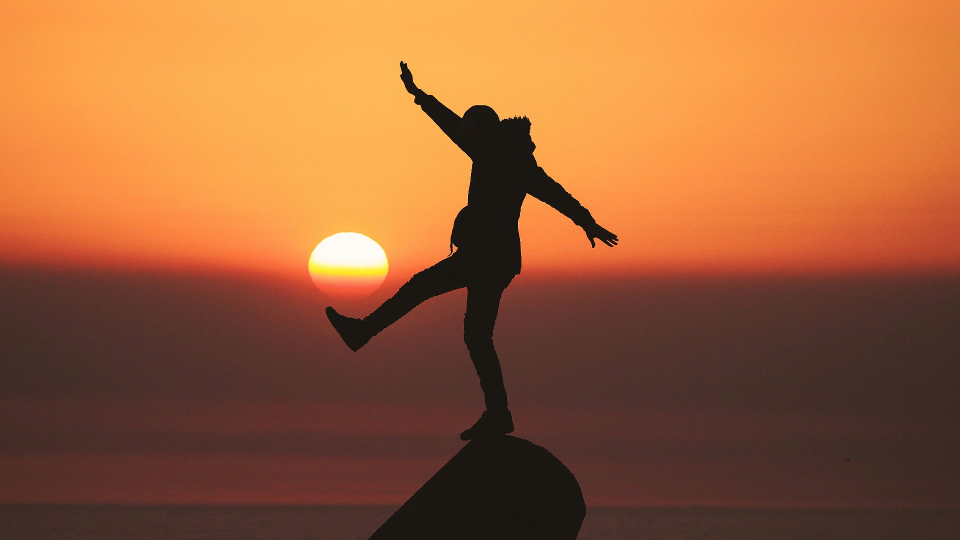 photo of silhouette photo of man standing on rock