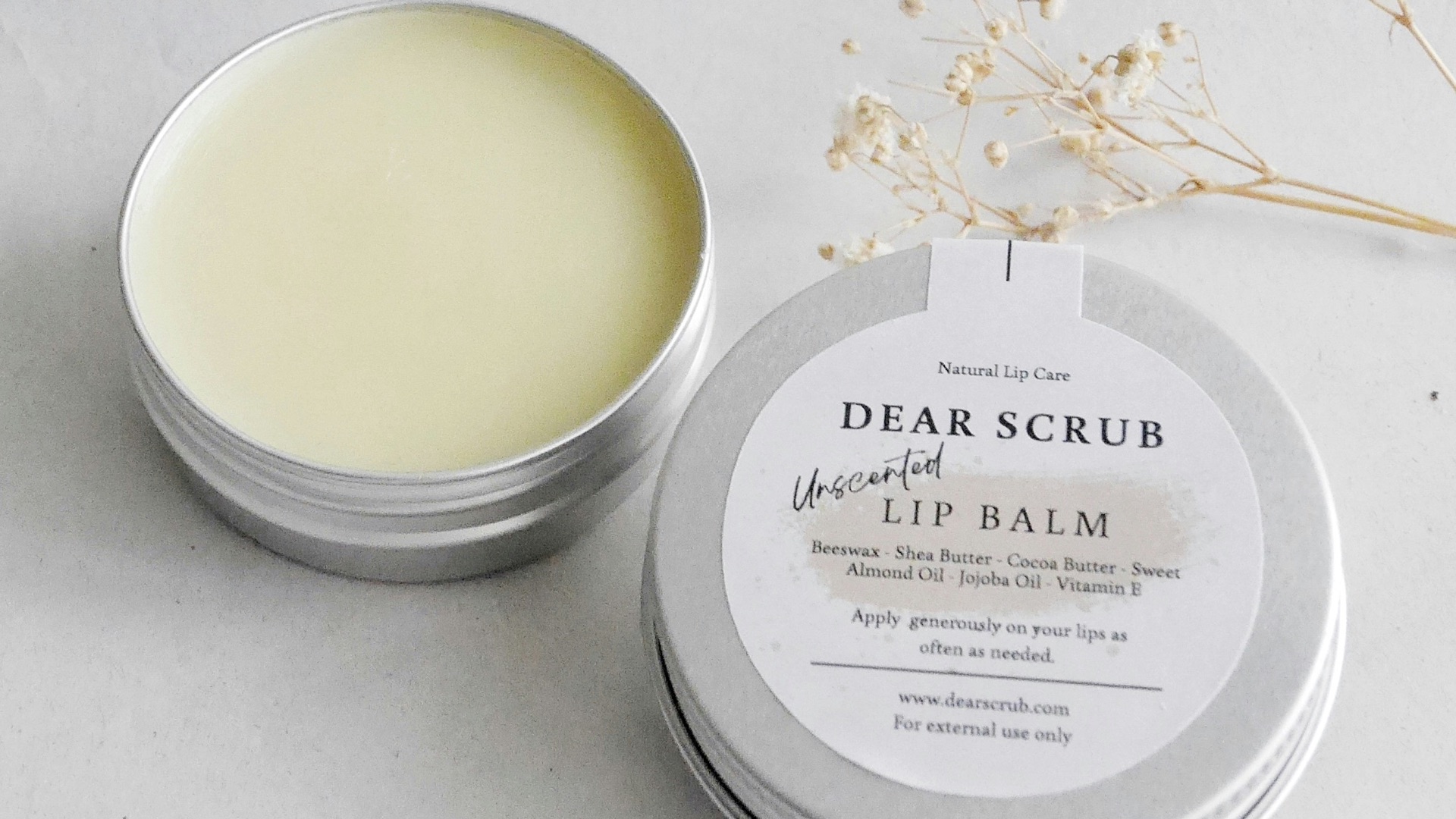 a tin of lip balm next to a flower