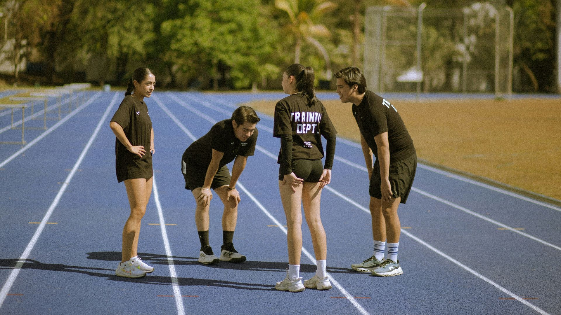 Four athletes in black on a blue running track