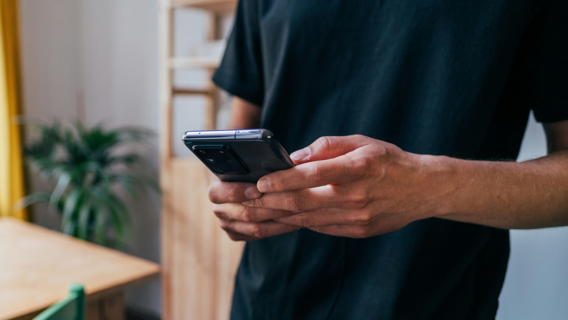 person in blue long sleeve shirt holding black smartphone