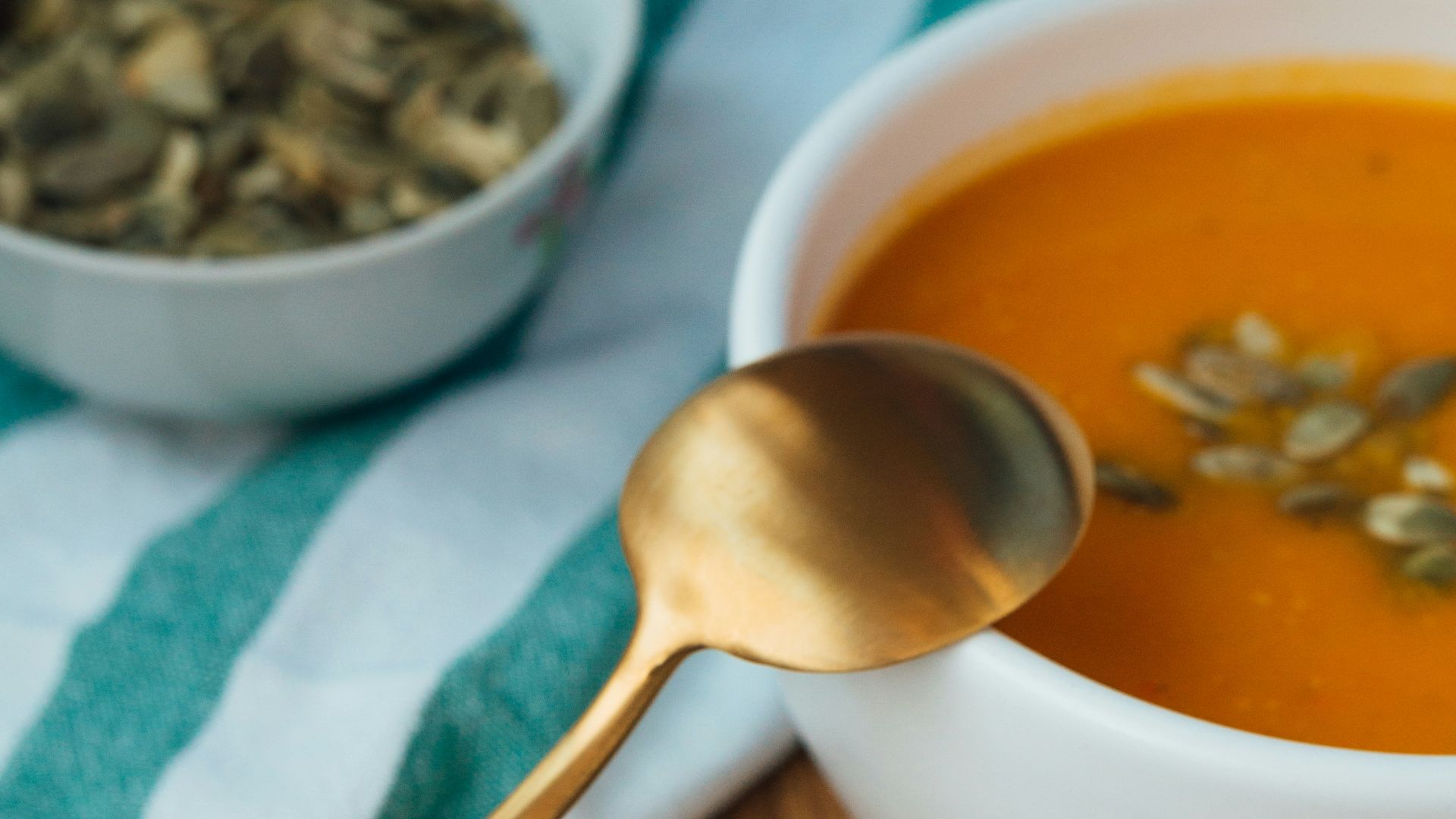 soup in white ceramic bowl beside stainless steel spoon