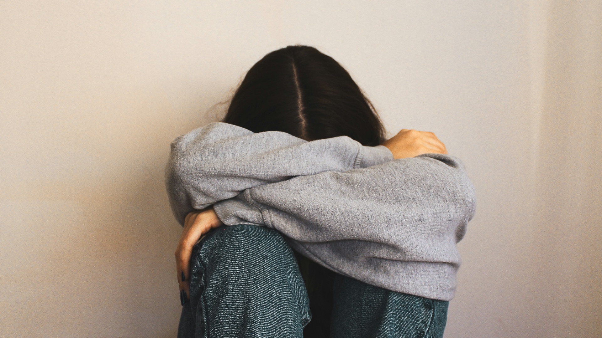 a woman sitting on the floor with her arms wrapped around her head
