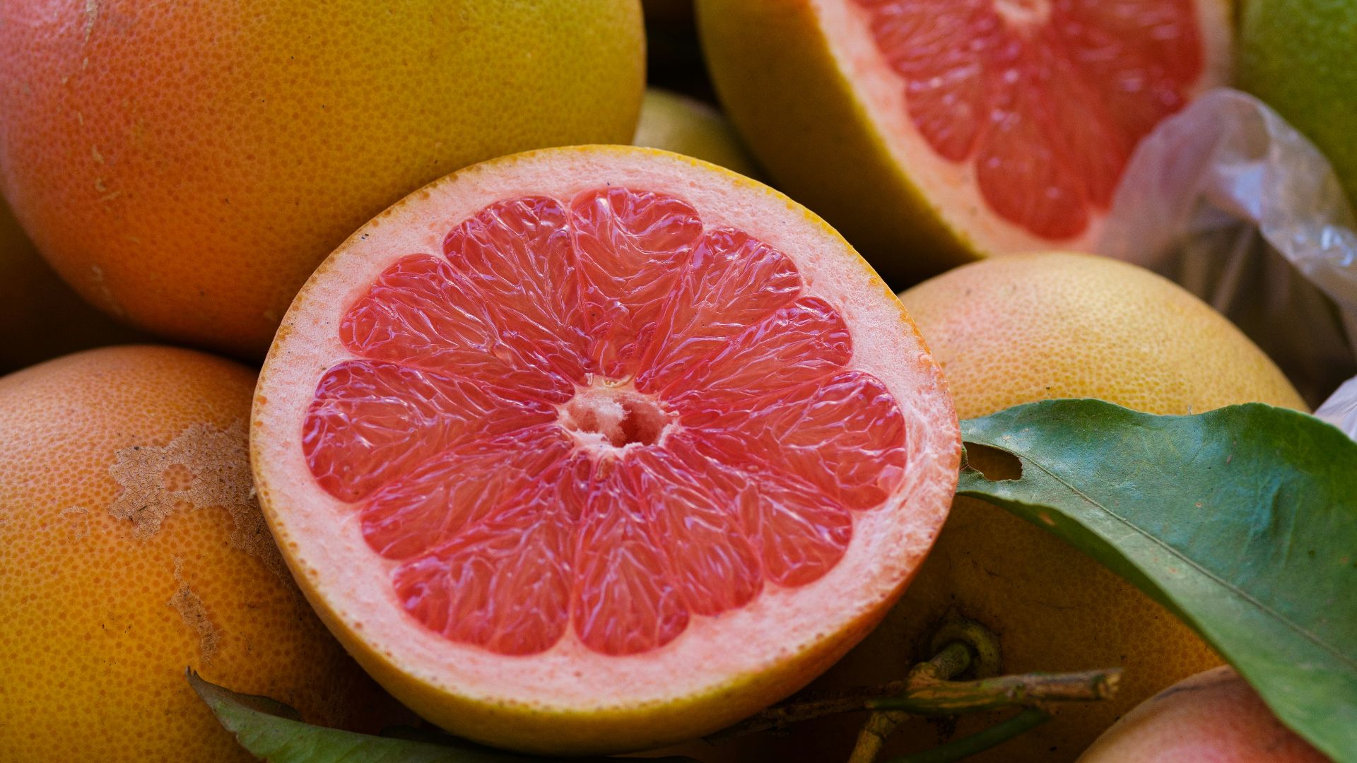 a pile of grapefruits with one cut in half