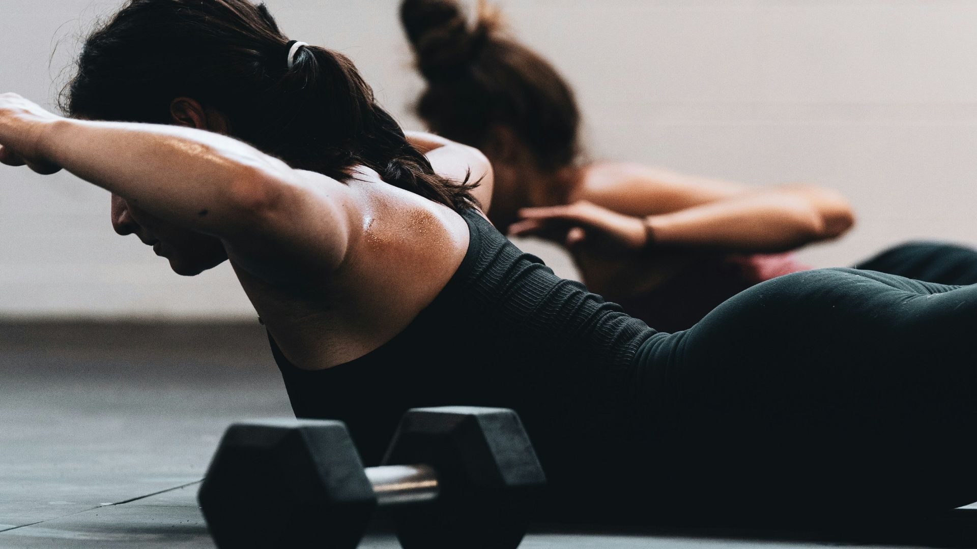 woman in black tank top and black leggings lying on black floor
