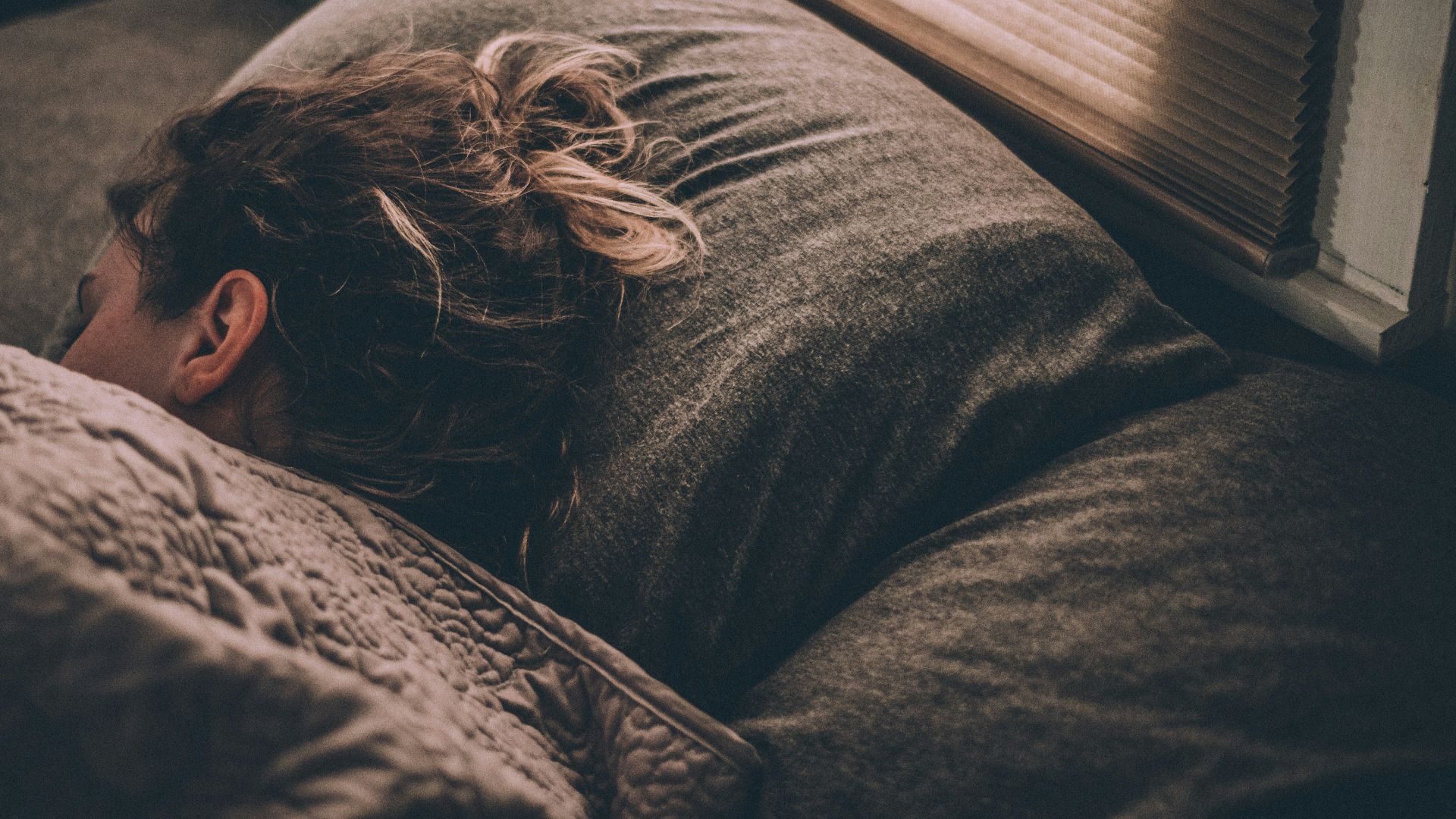 woman sleeping on bed under blankets