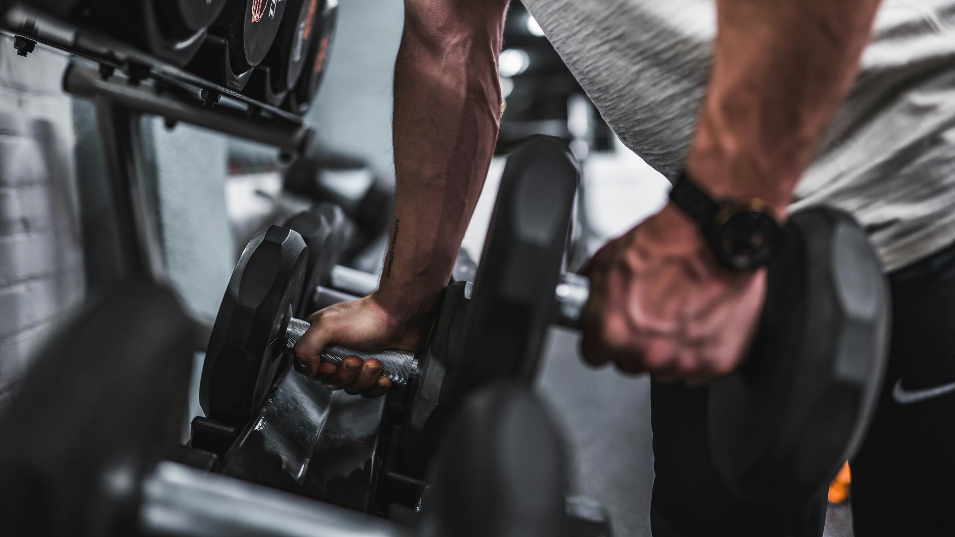 person in gray shirt holding black dumbbell