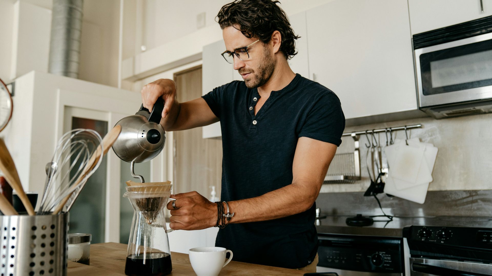 man in blue crew neck t-shirt pouring water on white ceramic teacup