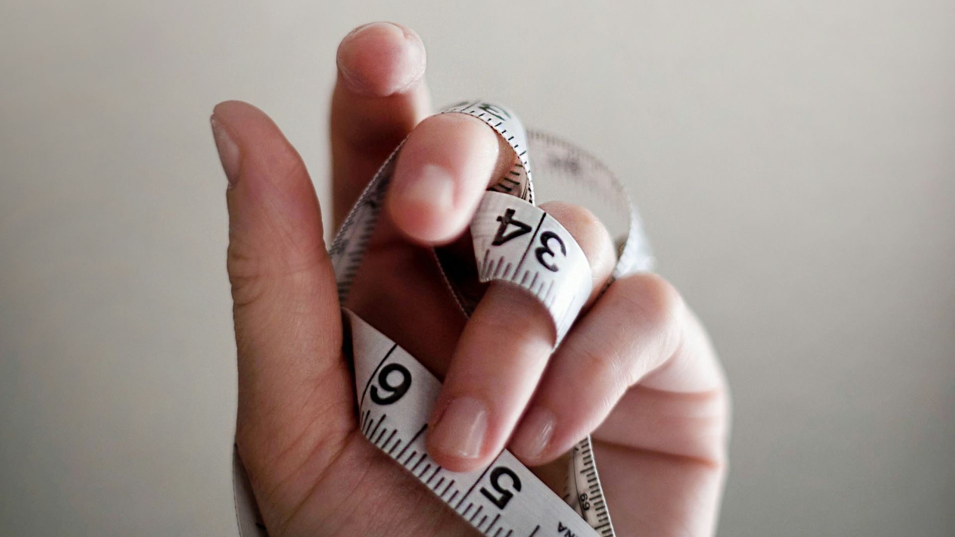 person's left hand wrapped by tape measure