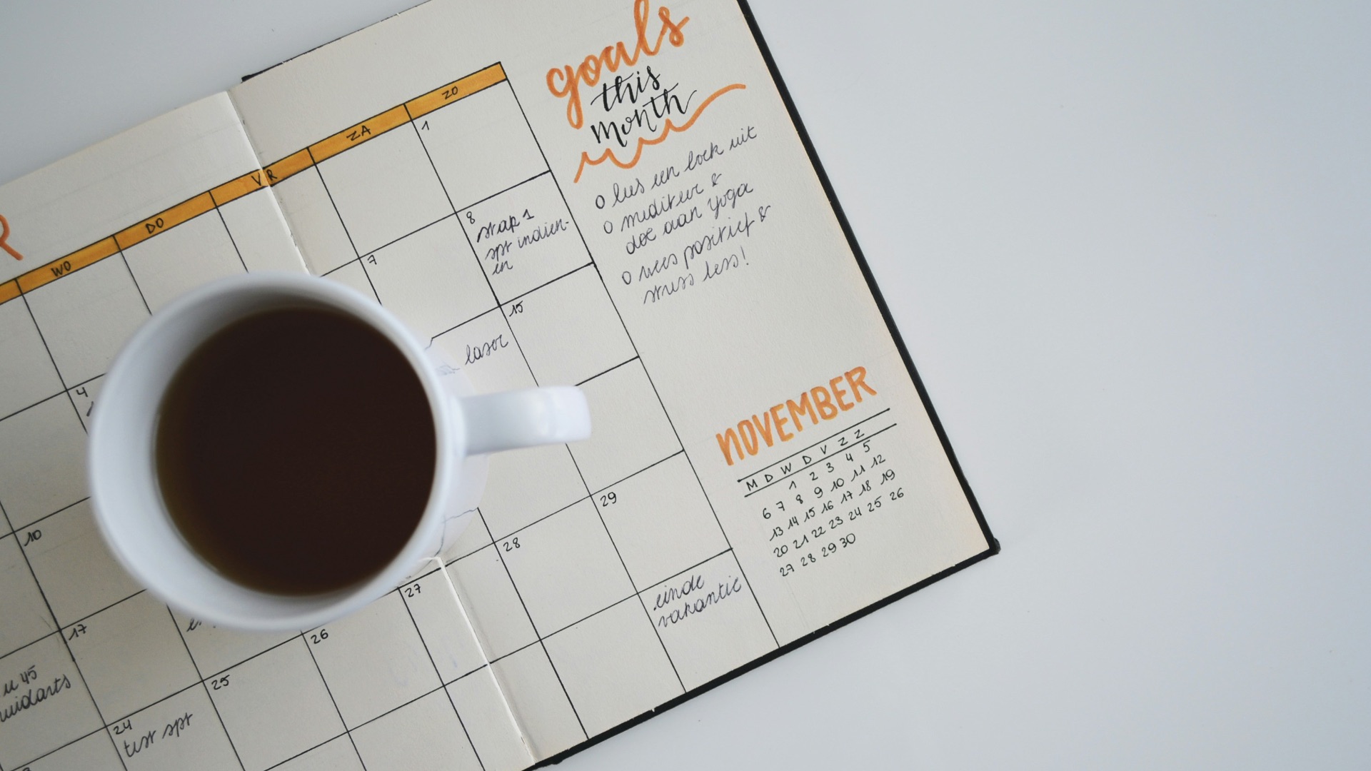 white ceramic mug with coffee on top of a planner