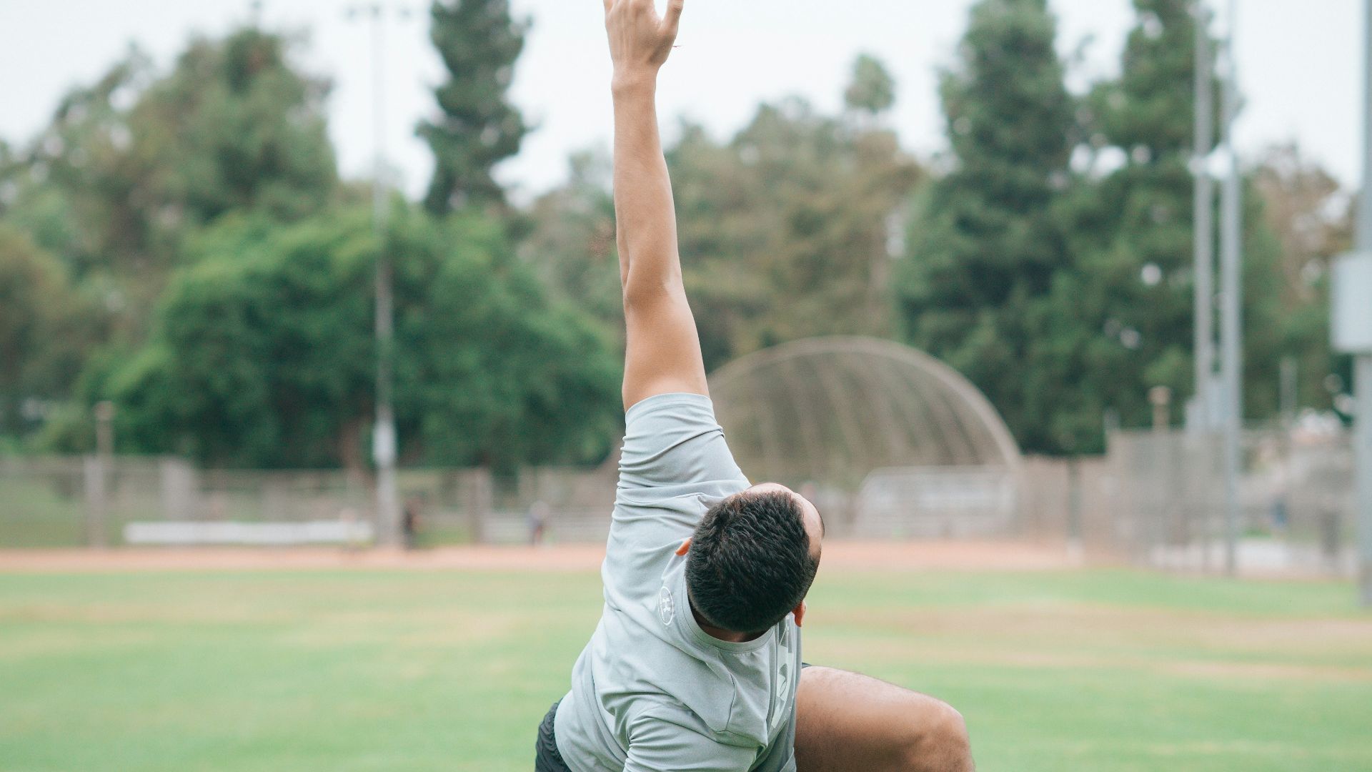 man in black and white t-shirt and black shorts sitting on green grass field during