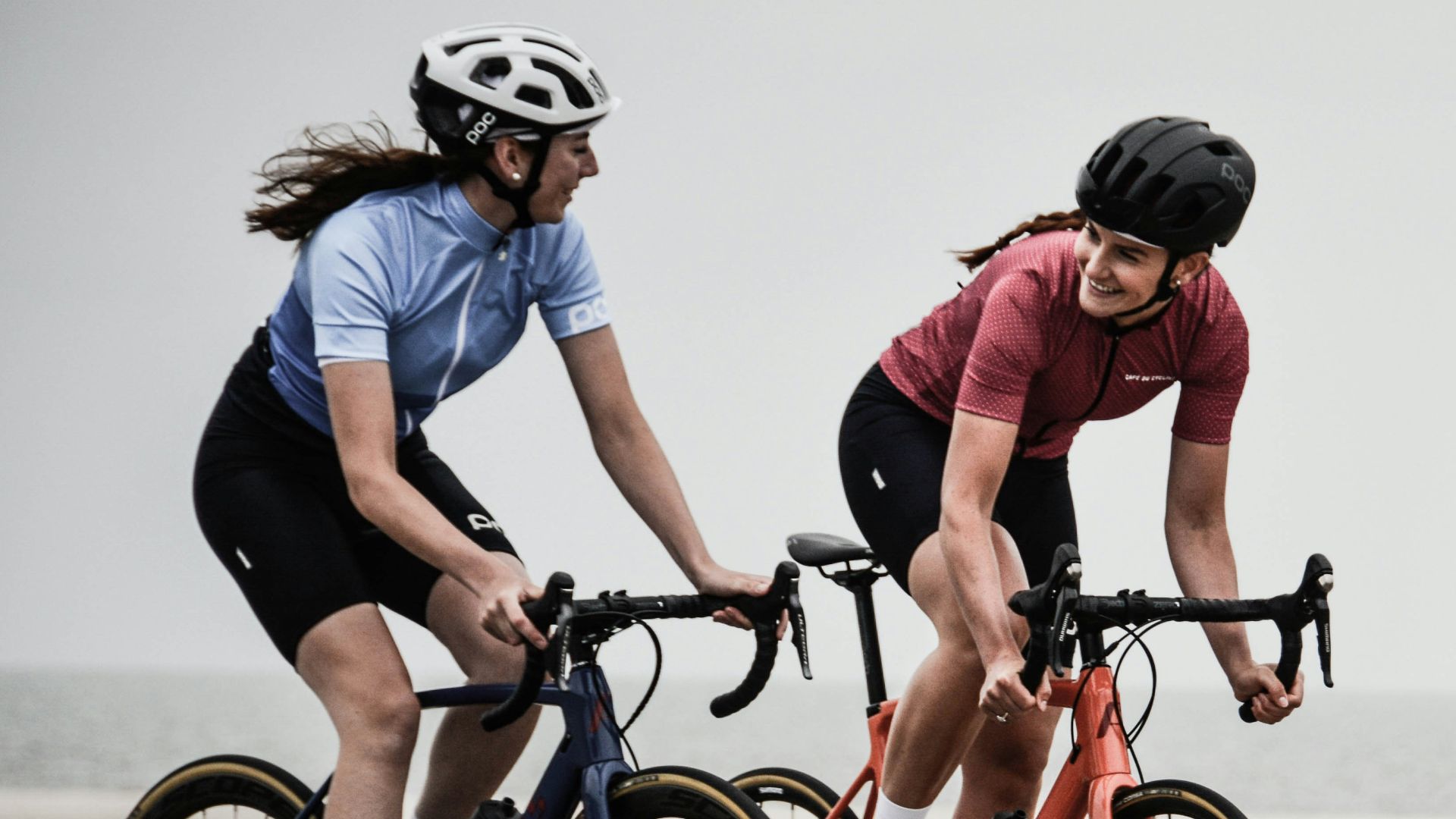 man and woman riding road bikes at the road near shore